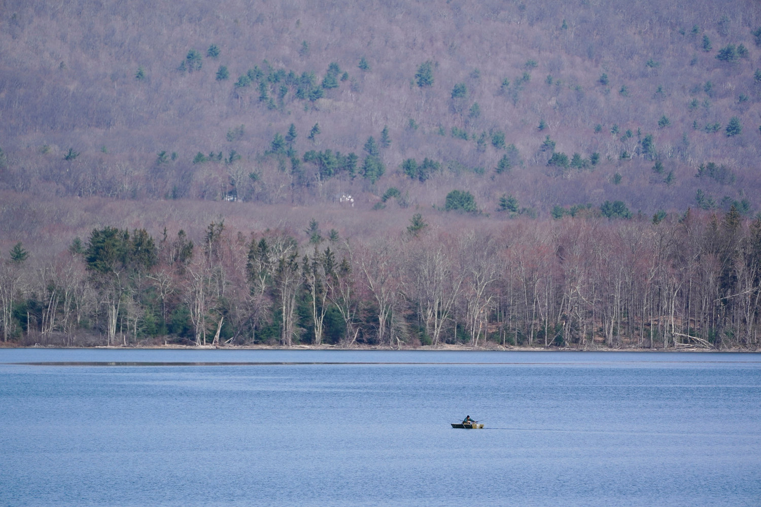 A rowboat makes its way on the surface of the Ashokan Reservoir in Olive, N.Y., Tuesday, April 5, 2022. As western regions contend with drier conditions, New York City is under fire for sometimes releasing hundreds of millions of gallons of water a day from the reservoir in the Catskill Mountains. The occasional releases, often around storms, have been used to manage water the reservoir's  levels and to keep the water clear. But residents downstream say the periodic surges cause ecological harm along the lower Esopus Creek. (AP Photo/Seth Wenig)