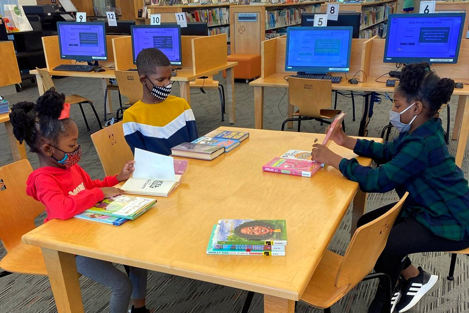 LESSON TIME — In this undated photo provided by Dalaine Bradley, Drew Waller, 7, Ahmad Waller, 11, and Zion Waller, 10, left to right, study at Cameron Village Library during homeschooling, in Raleigh, N.C.