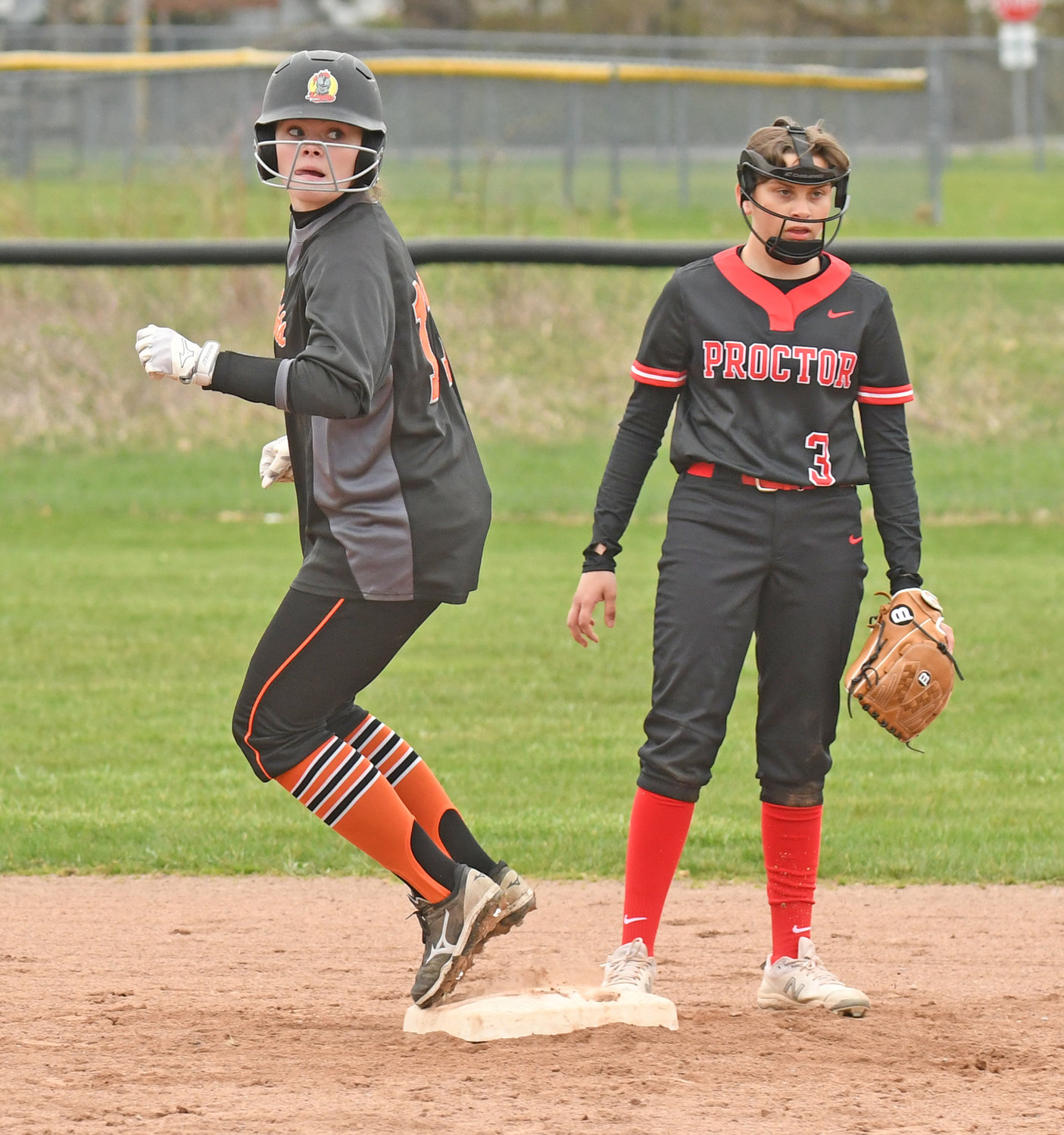 KNIGHTS SWEEP — Rome Free Academy baserunner Kelly O'Neil looks back to see the ball land in right field Tuesday against Utica Proctor at Kost Field in the first game of a doubleheader. Awaiting the throw in is Proctor shortstop Bianca Marino. RFA won both Tri-Valley League games, 5-0 and then 10-3.