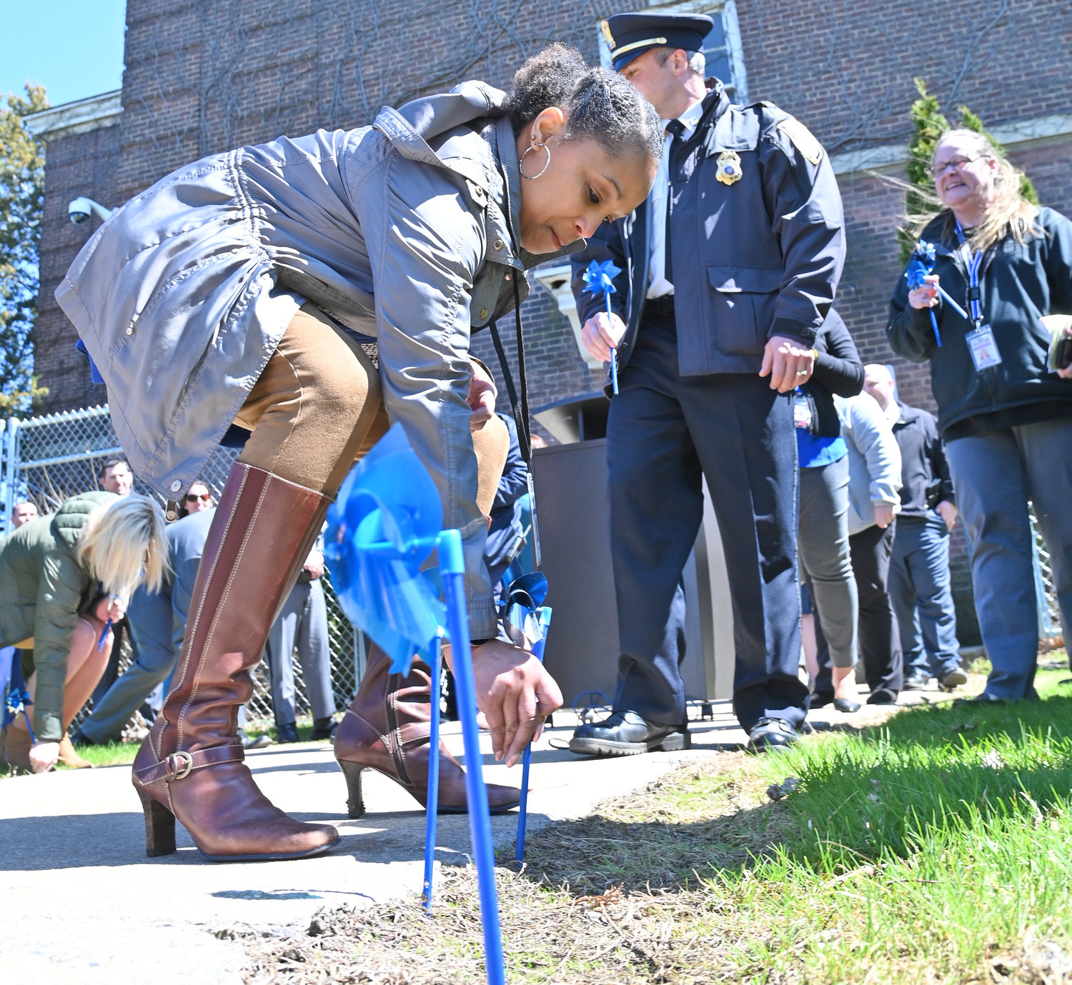 PINWHEELS TO REMEMBER — Krystal Harmon-Burton, an administrative assistant at Oneida County Child Advocacy Center, places a pinwheel into the ground during the ceremony on Thursday marking National Child Abuse Prevention Month. The CAC and local county leaders make this month every year with pinwheels to help spread awareness.