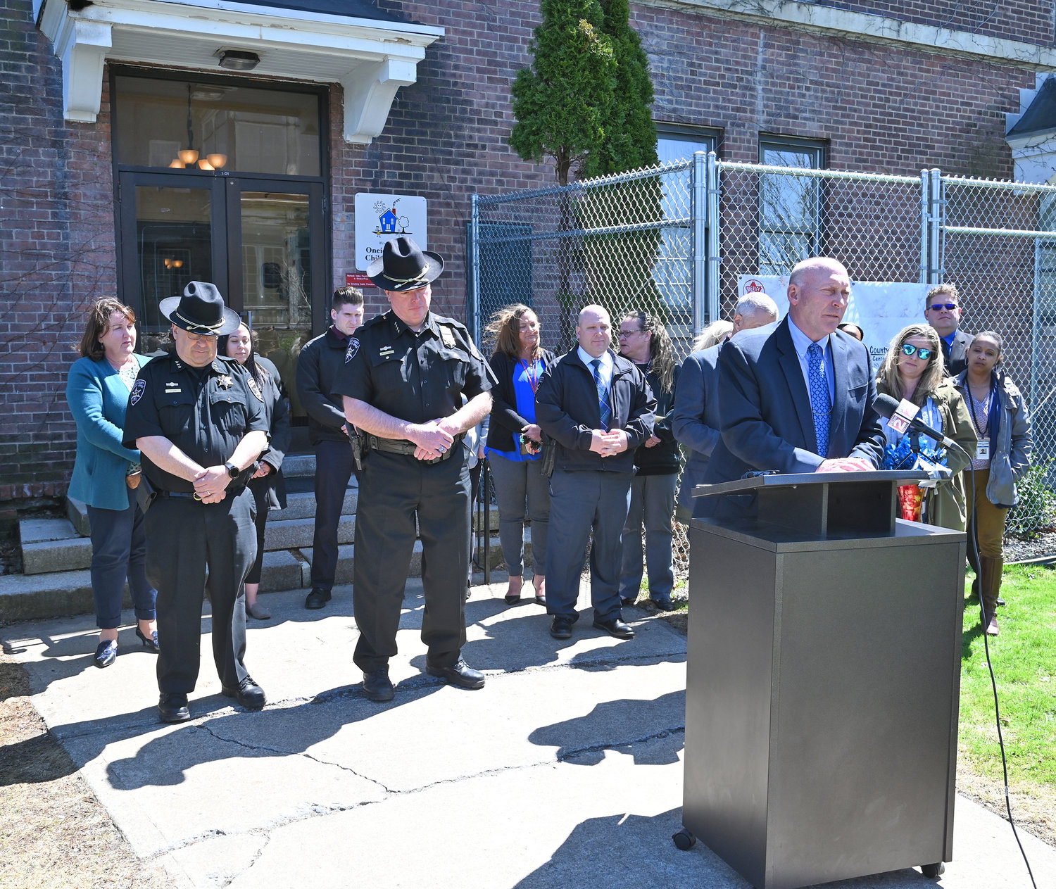 COUNTY LEADERS — Oneida County Chief Sheriff's Deputy Derrick O'Meara speaks on Thursday at the Child Advocacy Center, marking the end of National Child Abuse Prevention Month. O'Meara has been director of the agency for several years. He was joined by other county leaders, including Sheriff Robert M. Maciol, center, to make the occasion.