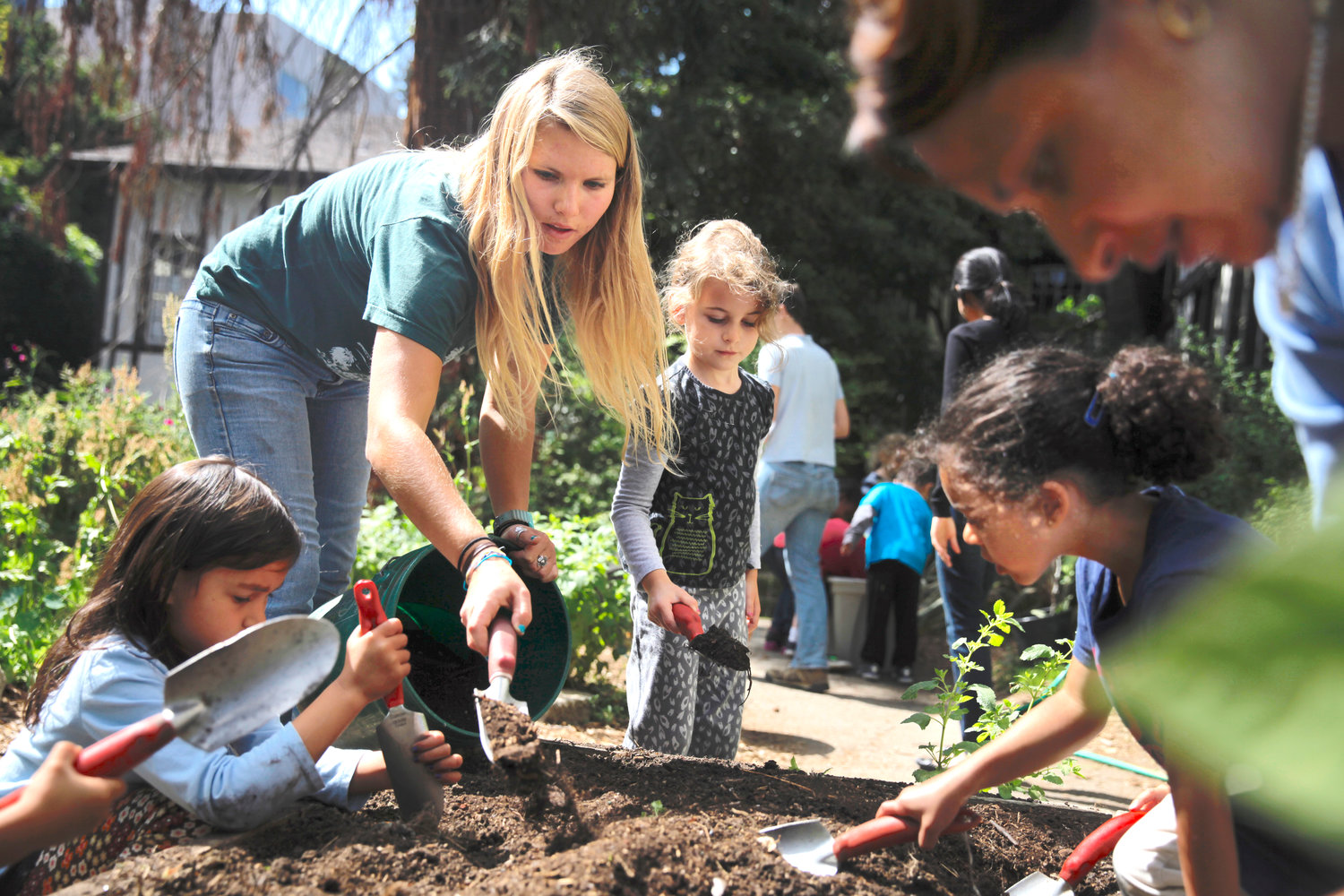 Jenny Wood (second from left), volunteer, shows High Five students how to mix compost with soil during class in the garden at John Muir Elementary School in Berkeley, Calif.