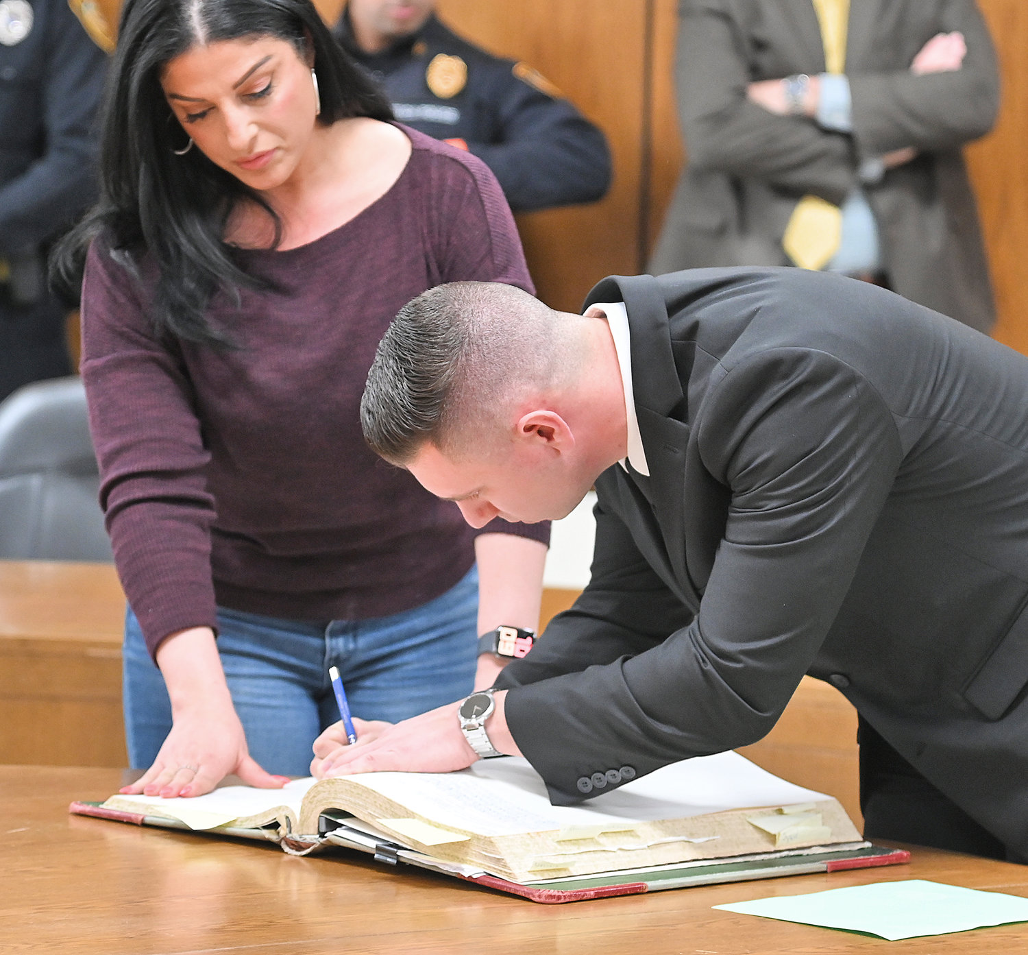 SIGNING IN — New recruit James Amuso signs the official Utica Police Department book, a longtime tradition for the agency for new members.