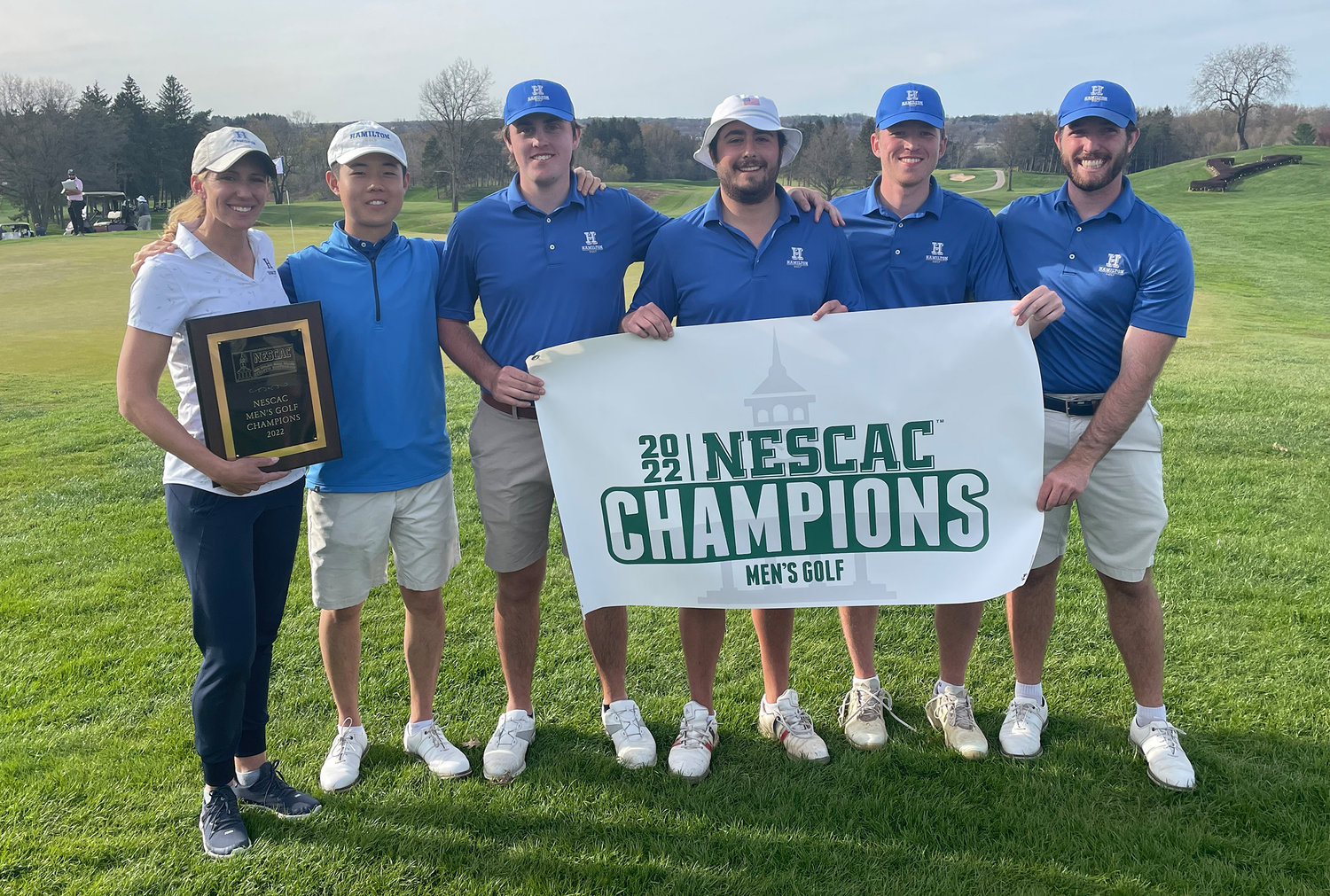 The Hamilton College men’s golf team displays the banner for the 2022 NESCAC championship the team won this past weekend, April 30 and May 1, at Yahnundasis Golf Club in New Hartford. The team is coached by Lauren Cupp, of Rome, at left.