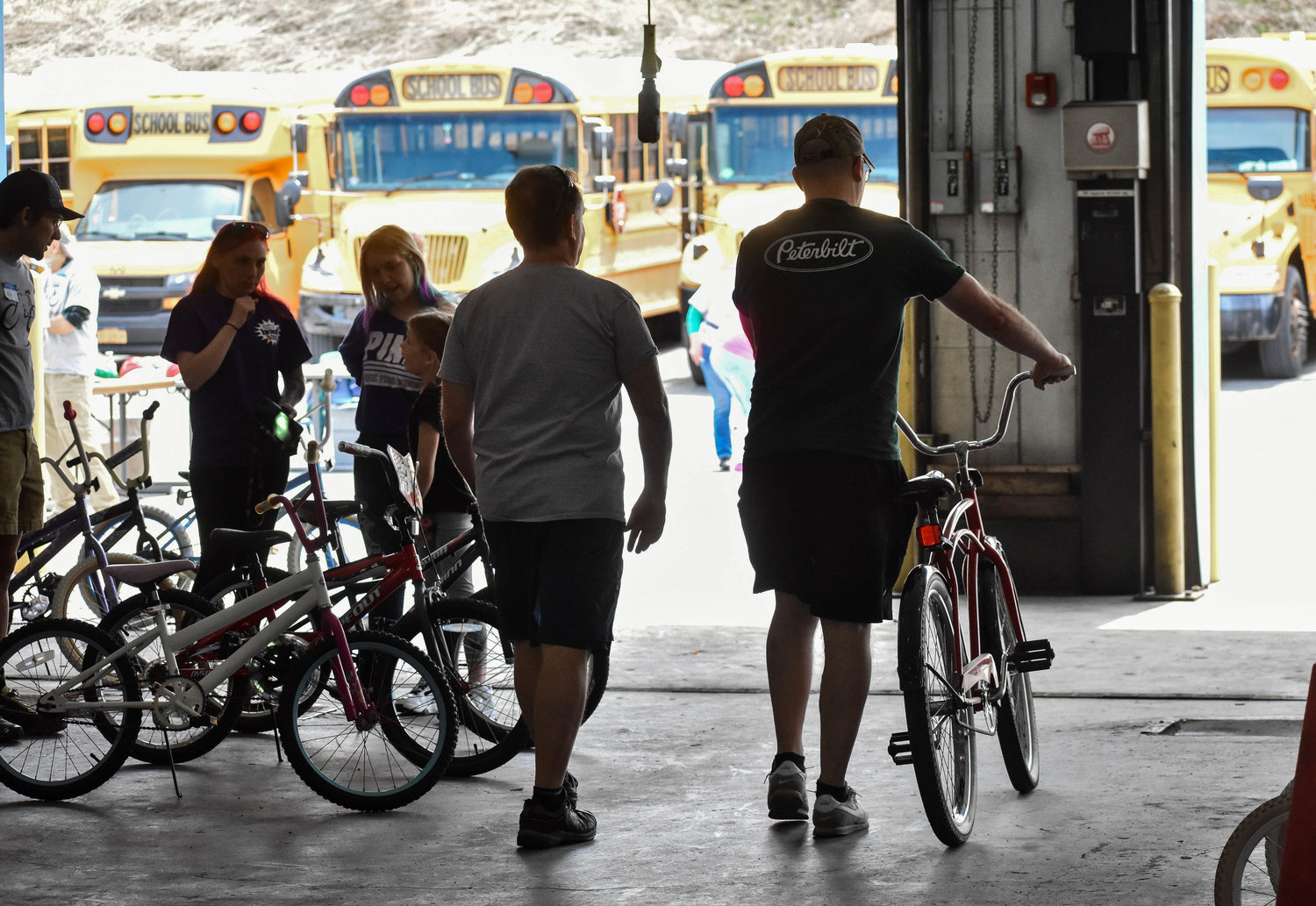 People young and old can benefit from owning a bike — to the left, a child picks from the selection at Community Bikes' distribution event. In the center, an adult takes his selected bike out for a test drive.