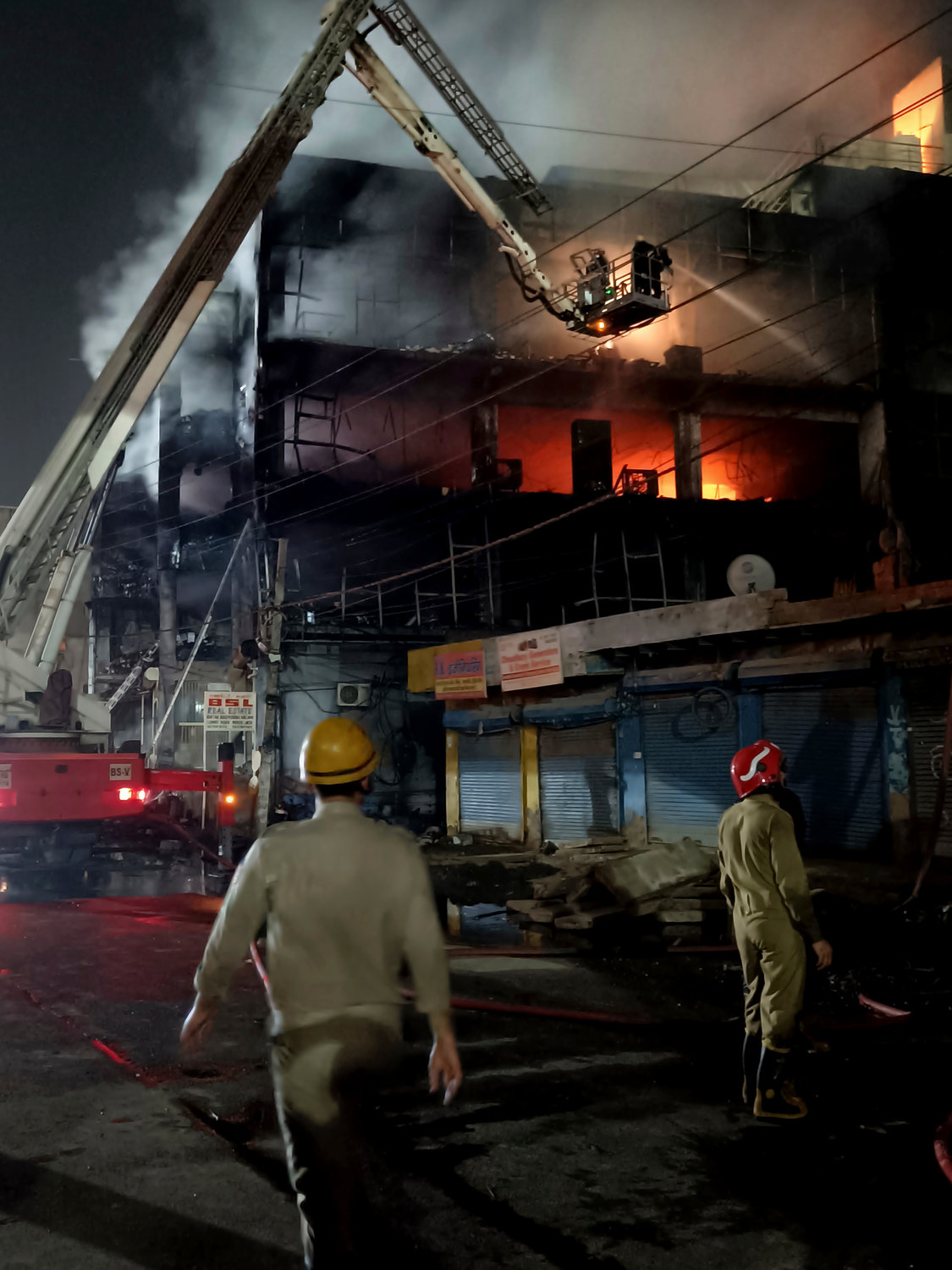 Fire officials try to douse a fire in a four storied building, in New Delhi, India, Friday, May 13, 2022. A massive fire erupted in a four-storied building in the Indian capital on Friday, killing at least 19 people and leaving several injured, the fire control room said. Dozens of people have been rescued from the commercial building, mainly shops, in the Mundka area in the western part of New Delhi. (AP Photo/Dinesh Joshi)