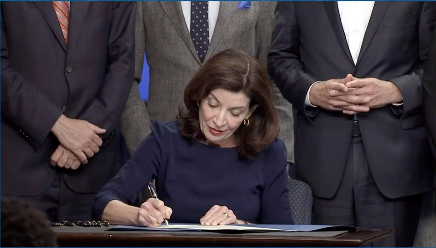 In this image taken from video, New York Gov. Kathy Hochul signs an executive order during a news conference, Wednesday, May 18, 2022, in New York.  New York would require state police to seek court orders to keep guns away from people who might pose a threat to themselves or others under a package of executive orders and gun control bills touted Wednesday by Hochul in the aftermath of a racist attack on a Buffalo supermarket.  (Office of the Governor of New York via AP)