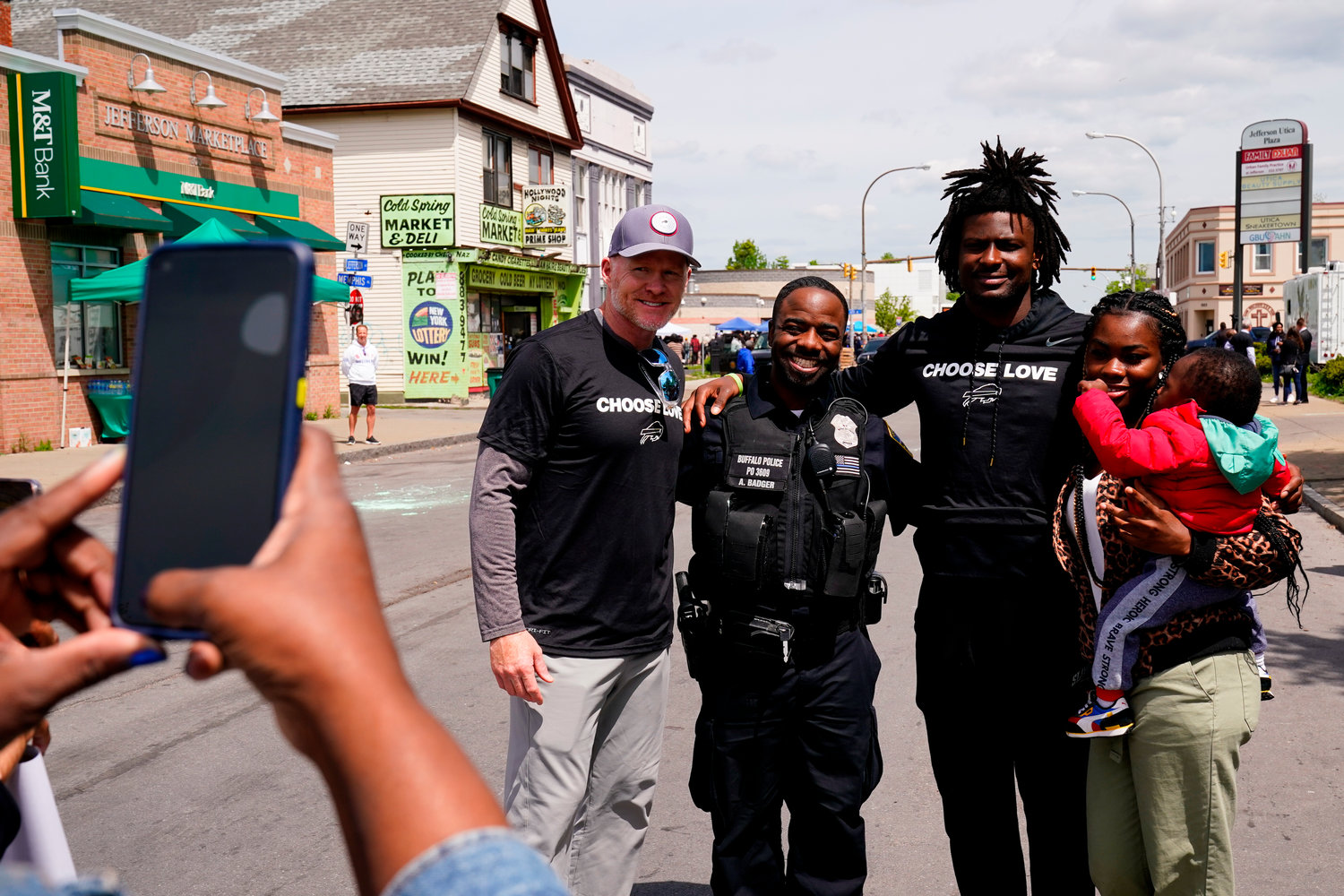 Buffalo Bills' Josh Thomas, second right, and coach Sean McDermott, center left, poses for a photograph near the scene of Saturday's shooting at a supermarket, in Buffalo, N.Y., Wednesday, May 18, 2022. (AP Photo/Matt Rourke)