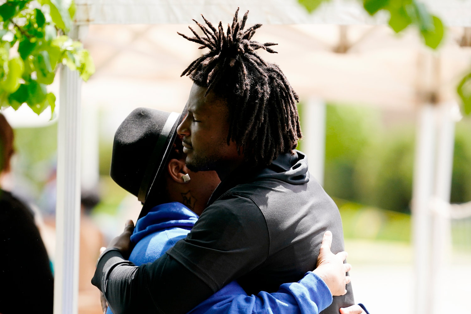 Buffalo Bills' Josh Thomas, right, embraces a person as he visits the scene of Saturday's shooting at a supermarket, in Buffalo, N.Y., Wednesday, May 18, 2022. (AP Photo/Matt Rourke)