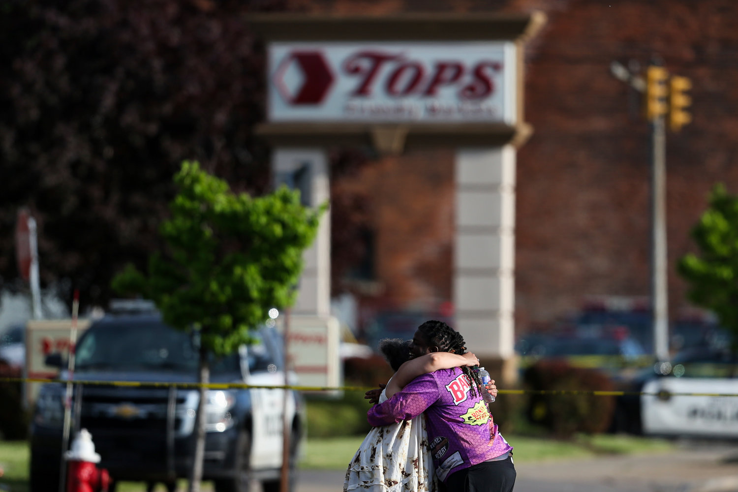 FILE - People hug outside the scene after a shooting at a supermarket on May 14, 2022, in Buffalo, N.Y.  The NAACP, the nation's oldest civil rights organization said it will propose a sweeping plan meant to protect Black Americans from white supremacist violence, in response to a hate-fueled massacre that killed 10 Black people in Buffalo, New York last weekend. (AP Photo/Joshua Bessex, File)