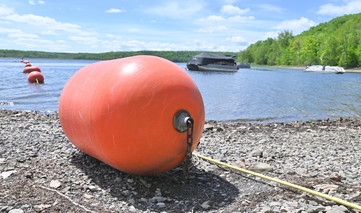 The Hinckley Reservoir is ready for the 2022 recreational season as the New York Power Authority has announced the opening of the popular boat launch.  Above a bouy rests on the shore as boats float along the placid surface of the reservoir in the back ground.