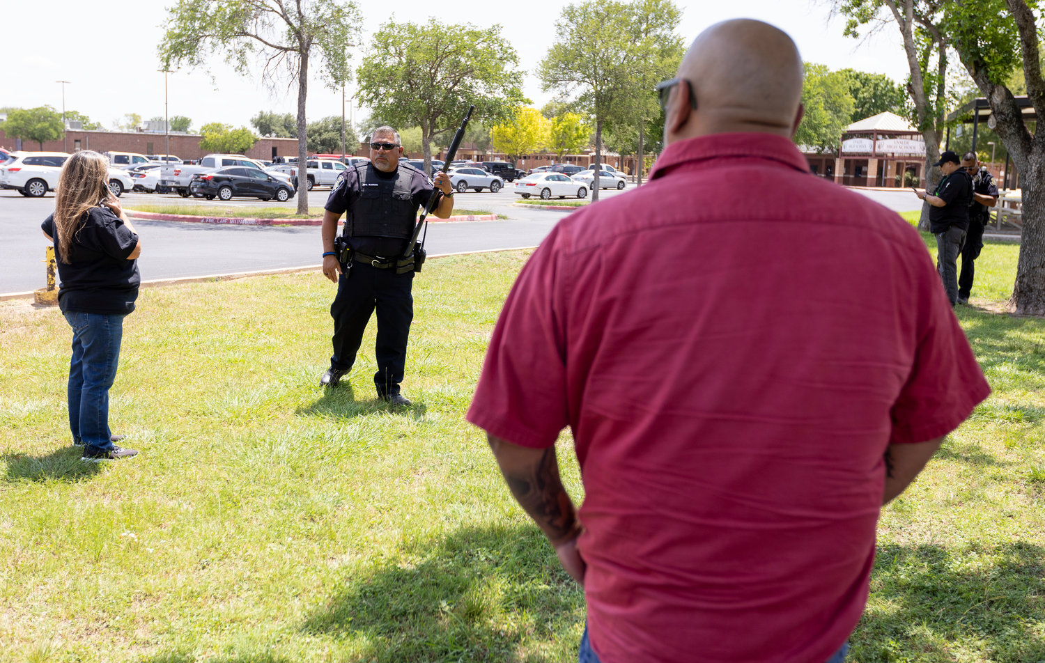 A law enforcement officer speaks with people outside Uvalde High School after shooting a was reported earlier in the day at Robb Elementary School, Tuesday, May 24, 2022, in Uvalde, Texas. (William Luther/The San Antonio Express-News via AP)