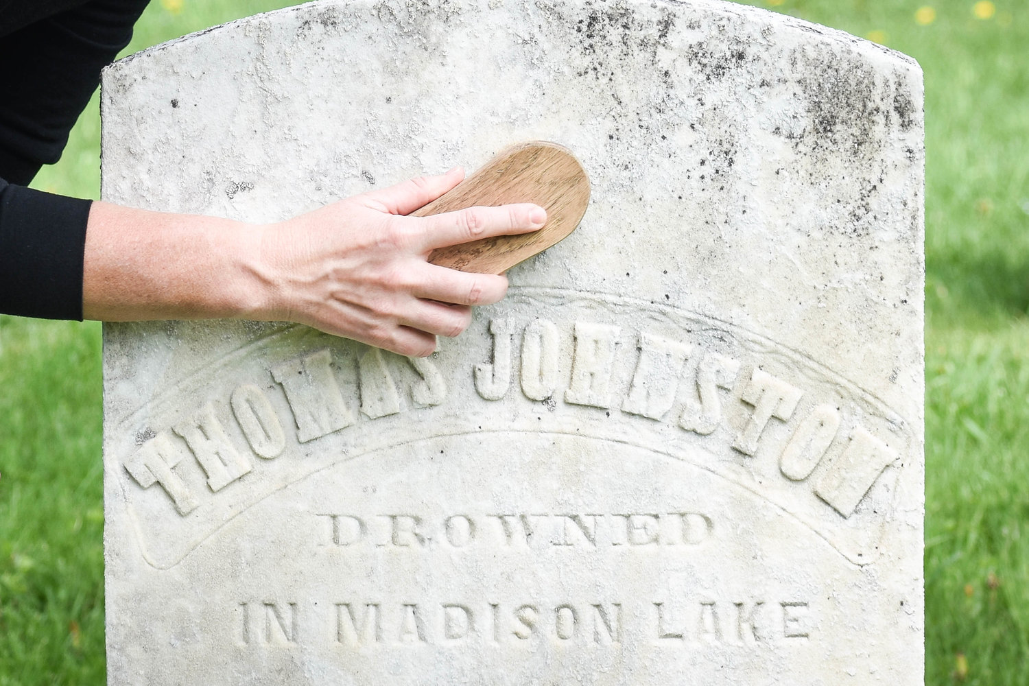 TikToker Megan Barnes brushes off a headstone she previously cleaned some time ago in Madison Village Cemetery. It takes weeks for the stone’s appearance to fully lighten to this degree after it has been cleaned with D/2 Biological Solution, Barnes explained. This is Thomas Johnston’s gravestone. Beneath it reads, “drowned in Madison Lake.”