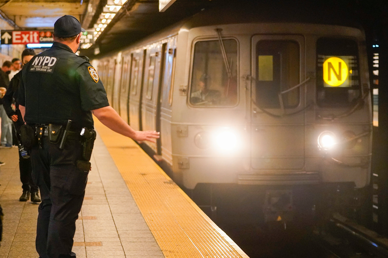 A New York Police Officers with the Transit Bureau Anti Terrorism Unit gestures to the train conducted as a train enters the Canal St. Q and N station, Tuesday, May 24, 2022, in New York. Andrew Abdullah, the man wanted in an apparently unprovoked fatal shooting aboard a New York City subway train was taken into custody by police on Tuesday, hours after authorities posted his name and photo on social media and implored the public to help find him. (AP Photo/Mary Altaffer)