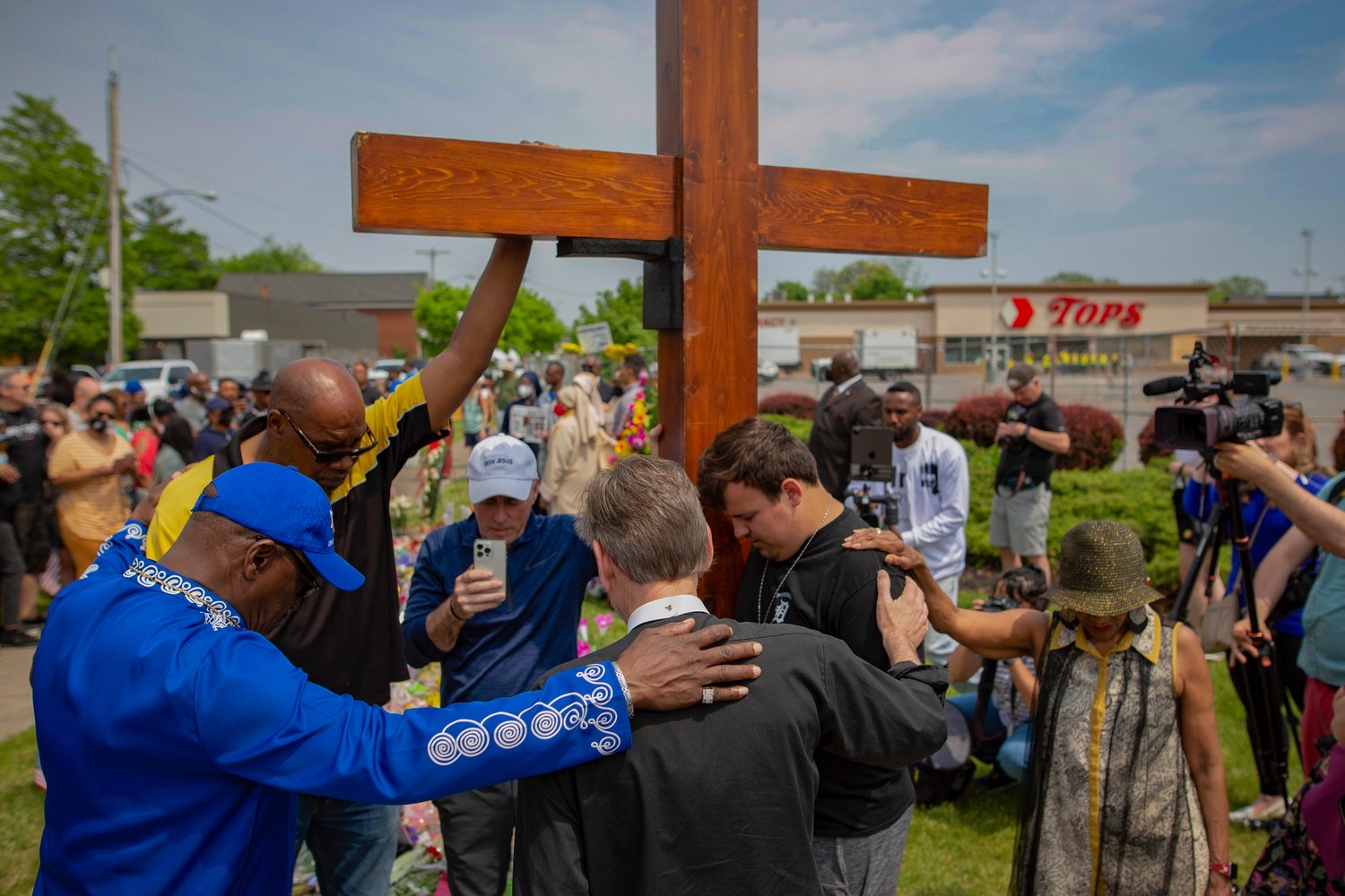 FILE - A group prays at the site of a memorial for the victims of the Buffalo supermarket shooting outside the Tops Friendly Market on Saturday, May 21, 2022, in Buffalo, N.Y. Funeral services are set for Friday for three of those killed: Geraldine Talley, Andre Mackniel and Margus Morrison. They are among the 10 people killed and three wounded May 14 when a white gunman opened fire on shoppers and employees at a Tops Friendly Market.