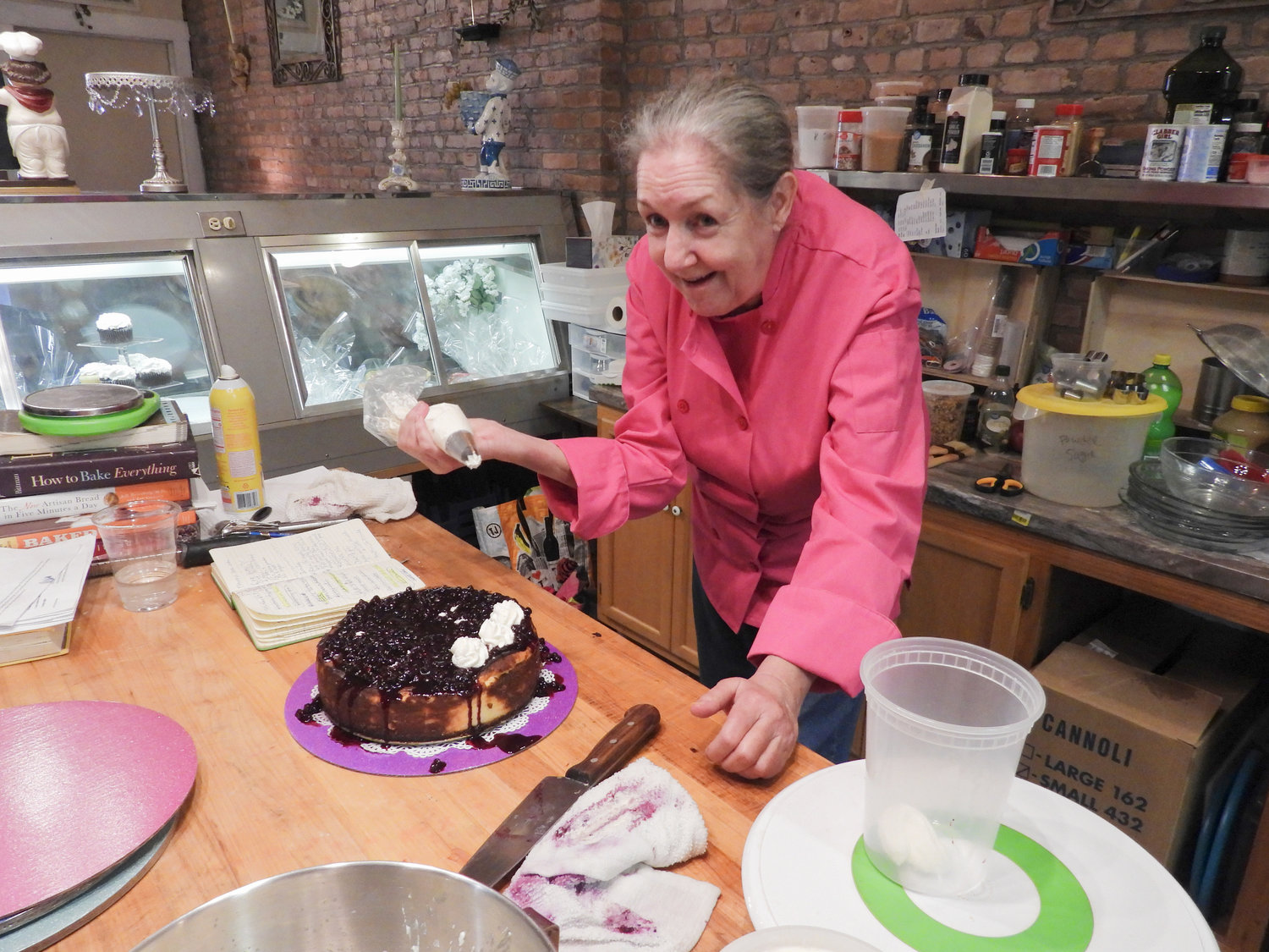 Head Baker Michelle French decorates her first blueberry cheesecake at Bella Vita Cafe, giving it a dollop of frosting for each slice.