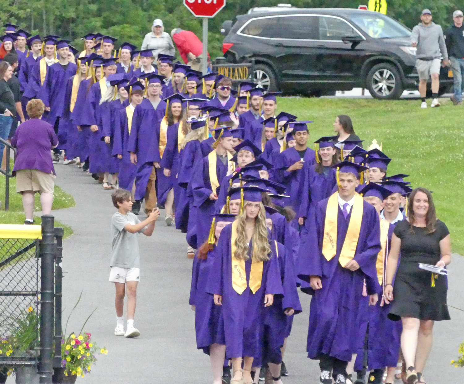 Seniors make their way down the walkway from the high school to the athletic complex in Holland Patent on Friday night, where 102 students received diplomas at the district’s 143rd Commencement Ceremony.