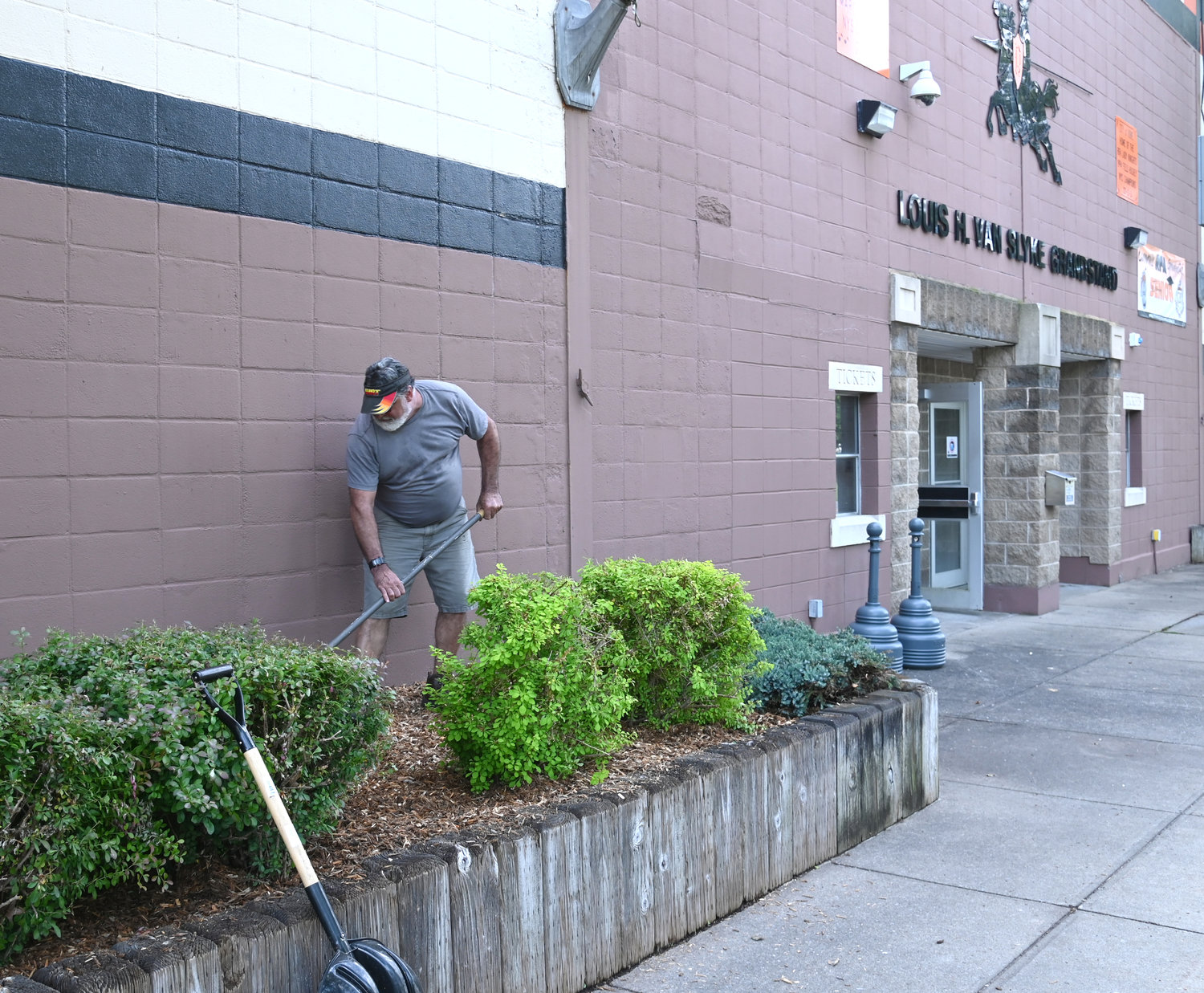 Michael Scuderi racks newly installed wood chips in a garden bed in front of RFA Stadium Friday June 17 in preparation for next weeks' graduation ceremony.
