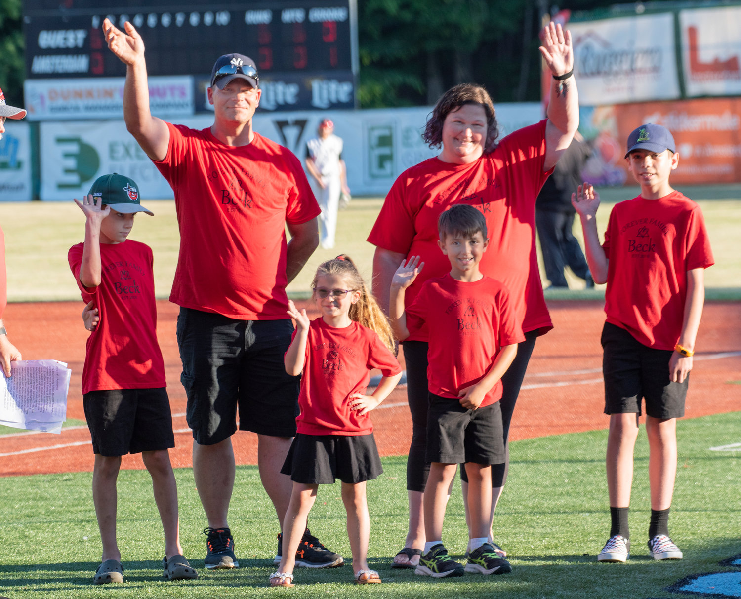 The Beck Family waves to the crowd as they were honored for their years as a foster family and their recent adoption of Audrianna, front center, after she threw out the first pitch at Tuesday, June 14, at the Amsterdam Mohawks game at Shuttleworth Park in Amsterdam.