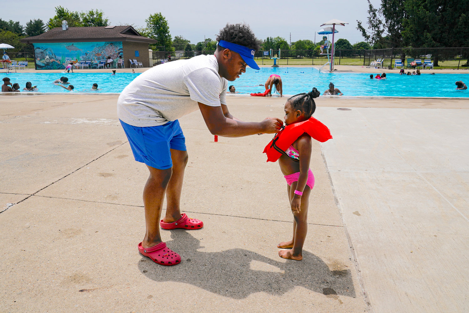 Lifeguard Donald Harris, 17, helps a swimmer with her lifejacket at the Douglass Park pool in Indianapolis, Friday, June 17, 2022. Indianapolis typically fills 17 pools each year, but with a national lifeguard shortage exacerbated by the COVID-19 pandemic, just five are open this summer. The American Lifeguard Association estimates one-third of pools in the United States are impacted by the shortage. (AP Photo/Michael Conroy)