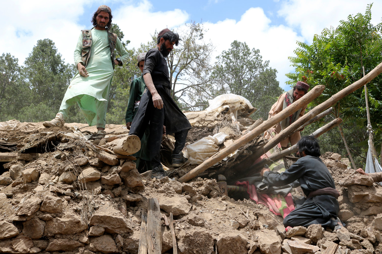 Afghan villagers collects belongings from under the rubble of a home that was destroyed in an earthquake in the Spera District of the southwestern part of Khost Province, Afghanistan, Wednesday, June 22, 2022. A powerful earthquake struck a rugged, mountainous region of eastern Afghanistan early Wednesday, killing at least 1,000 people and injuring 1,500 more in one of the country's deadliest quakes in decades, the state-run news agency reported. (AP Photo)