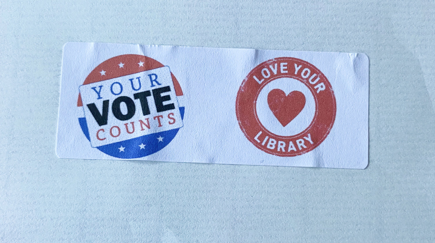 Local residents address the Vernon-Verona-Sherrill School Board, asking board members not to accept the Sherrill-Kenwood Free Library's budget vote amid accusations of electioneering. Pictured is the sticker in question