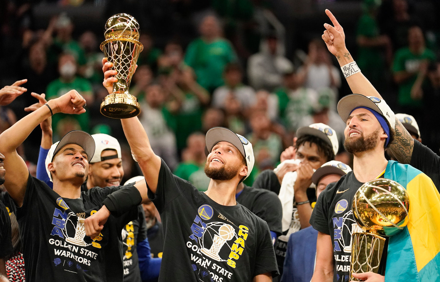 Golden State Warriors guard Stephen Curry, center, holds up the Bill Russell Trophy for most valuable player after the Warriors defeated the Boston Celtics in Game 6 to win basketball's NBA Finals championship, Thursday, June 16, 2022, in Boston.