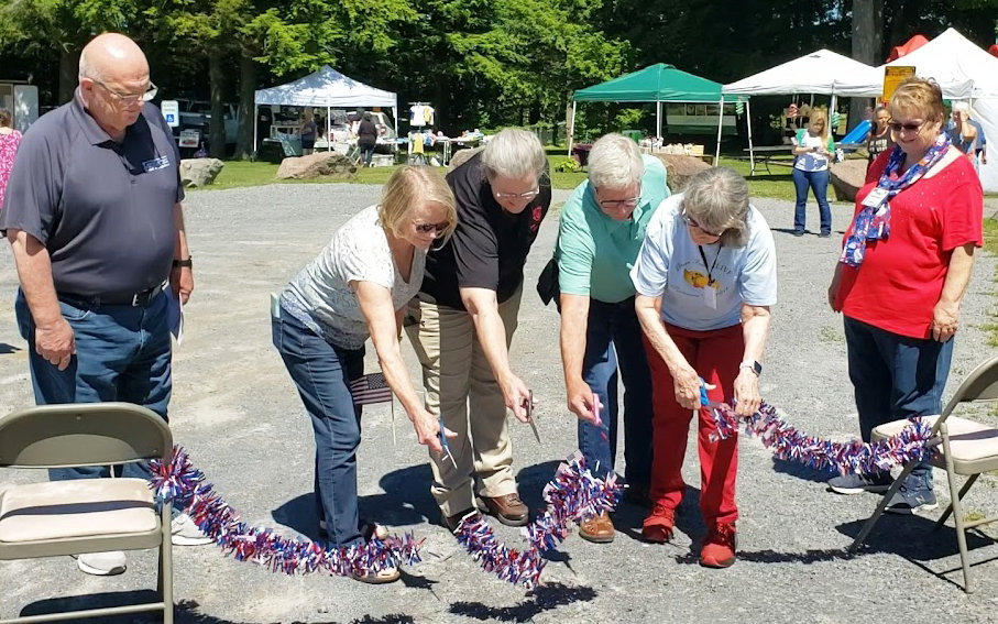 The Lyons Falls Farmers Market, sponsored by Lyons Falls ALIVE, officially opened with a ribbon-cutting ceremony at 11 a.m. on Tuesday, June 14. Pictured from left: Tom Osborne, Lewis County Legislator of District 9; Donna Dolhof; Michelle Ledoux; Lawrence Dolhof, Lewis County Chairman of Legislators; Katie Liendecker, manager of farming and baking vendors; and Patty Corey, manager of craft vendors. Jennifer Jones, commissioner of the Lewis County DSS, was also present at the ceremony.