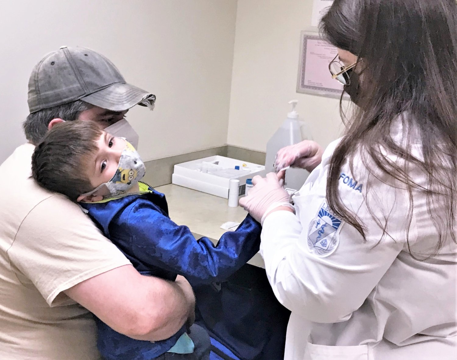 Lake Erie College of Medicine student Valerie Fiore performs a free lead screening on Lincoln Malloy, 5, at the Economic Opportunity Office in Elmira while his father Steven Malloy, of Horseheads, looks on.