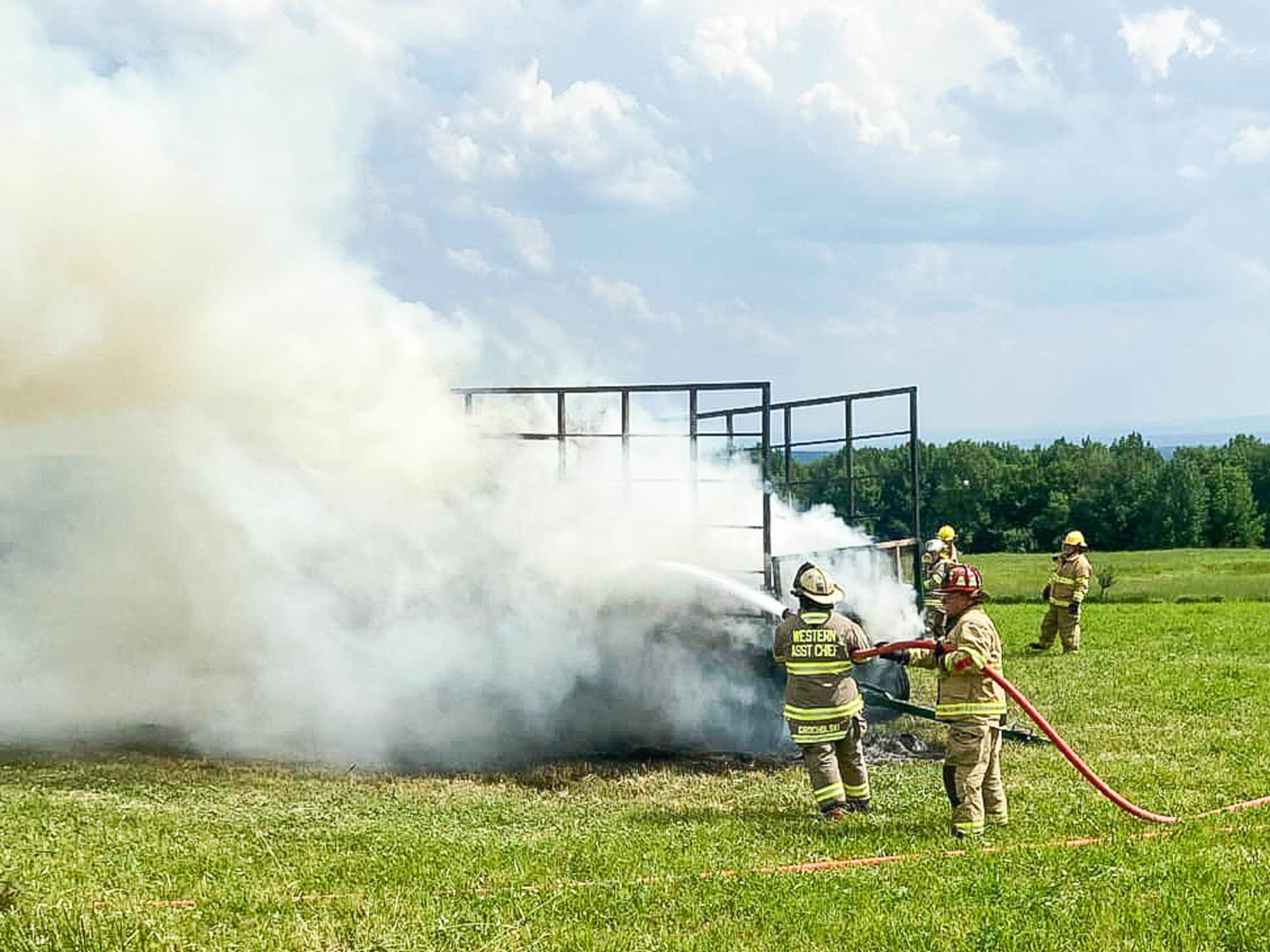 Town of Western firefighters douse a hay wagon fire on Quaker Hill Road at about 3:30 p.m. on Sunday. Temperatures reached nearly 90 degrees Sunday afternoon, and fire officials said hay is sometimes known to spontaneously combust when packed tightly in the heat. Once doused, authorities said the hay was dug out and spread across the ground to water down again.