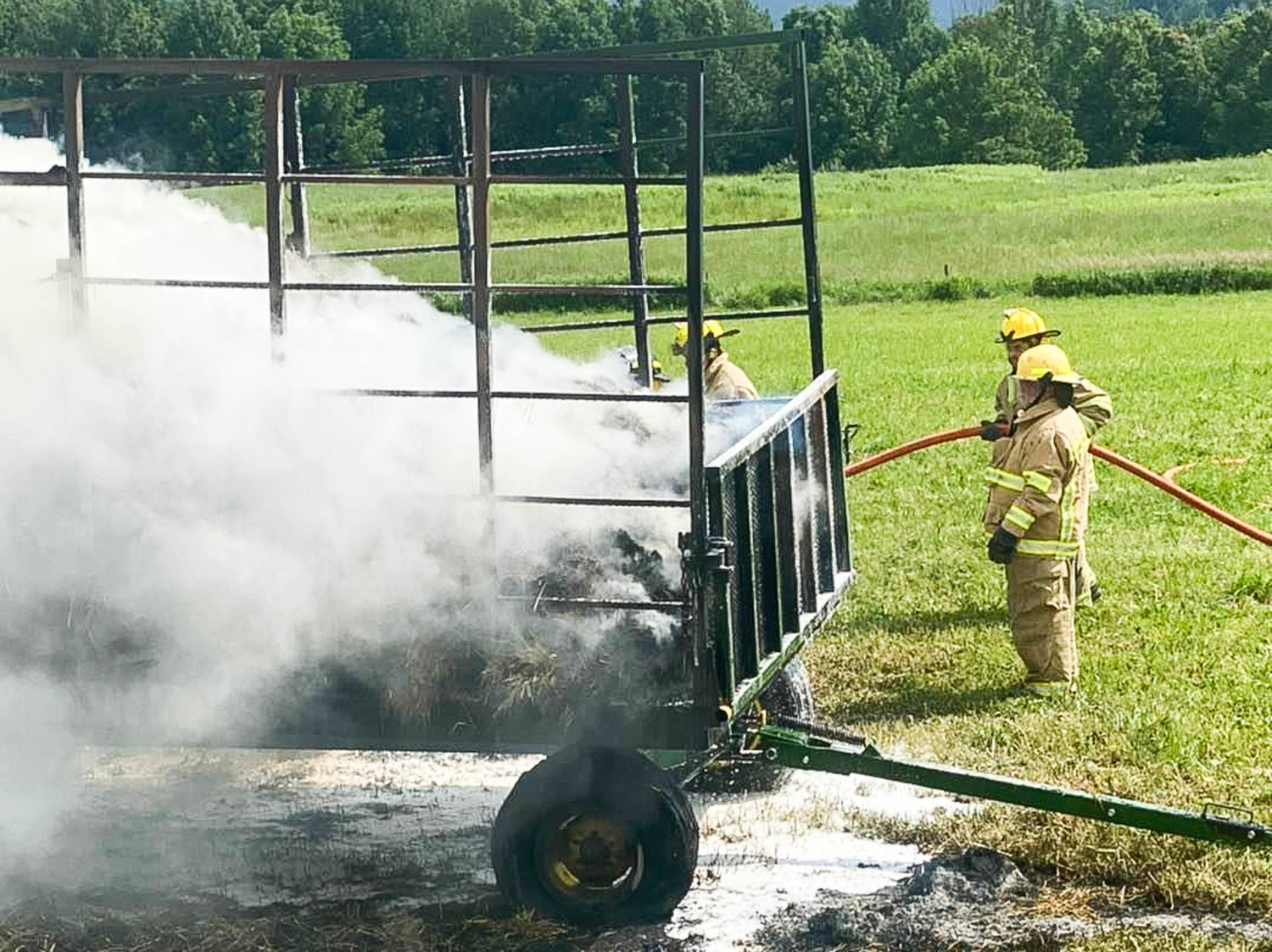 Town of Western firefighters douse a hay wagon fire on Quaker Hill Road at about 3:30 p.m. on Sunday. Temperatures reached nearly 90 degrees Sunday afternoon, and fire officials said hay is sometimes known to spontaneously combust when packed tightly in the heat. Once doused, authorities said the hay was dug out and spread across the ground to water down again.