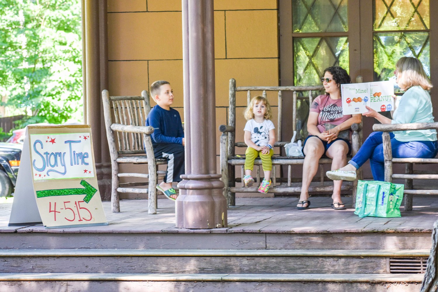 Left to right: Eight-year-old Henrik Ritter, three-year-old Marliese Ritter, and Sarah Mastrolia  enjoy story time on the front steps of the Madison County Historical Society while visiting the farmer's market on the front lawn on Tuesday.