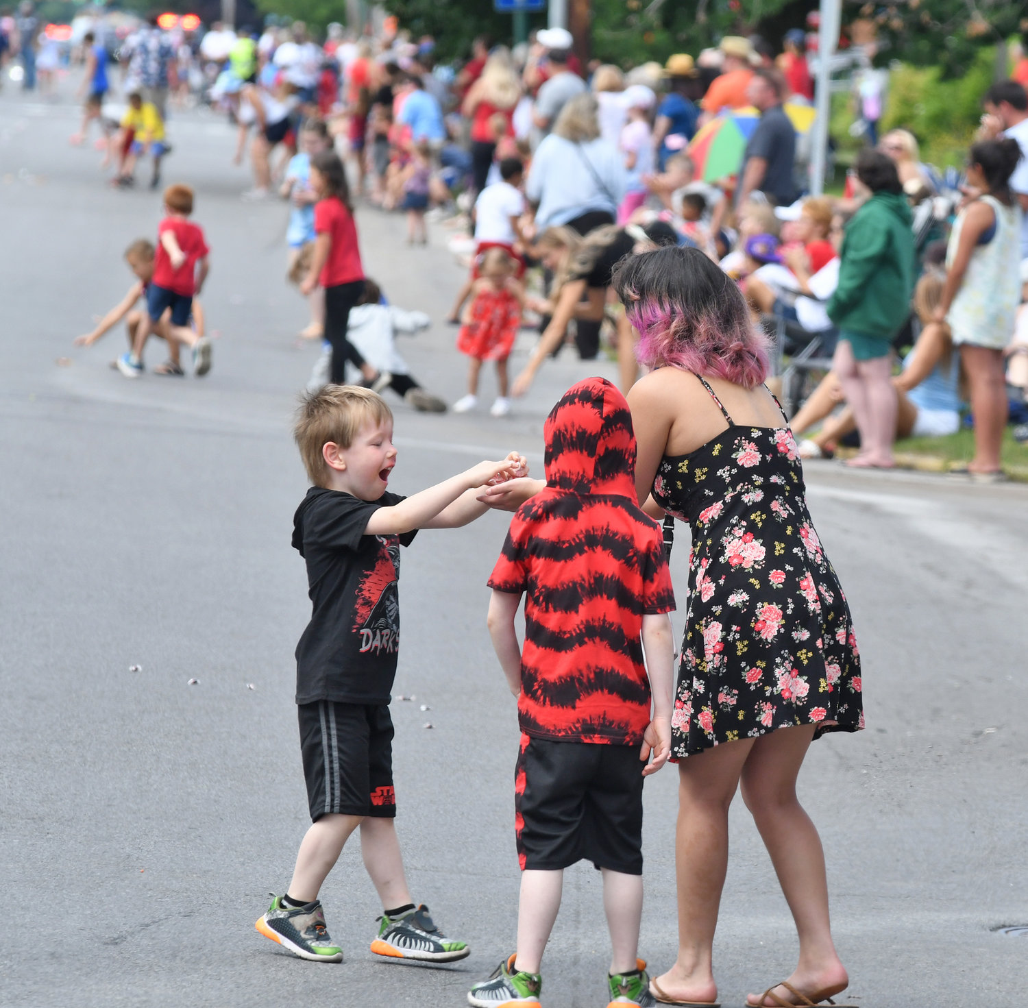 Fourth of July parade watchers collect the candy that was thrown out for them along the Genesee Street route.