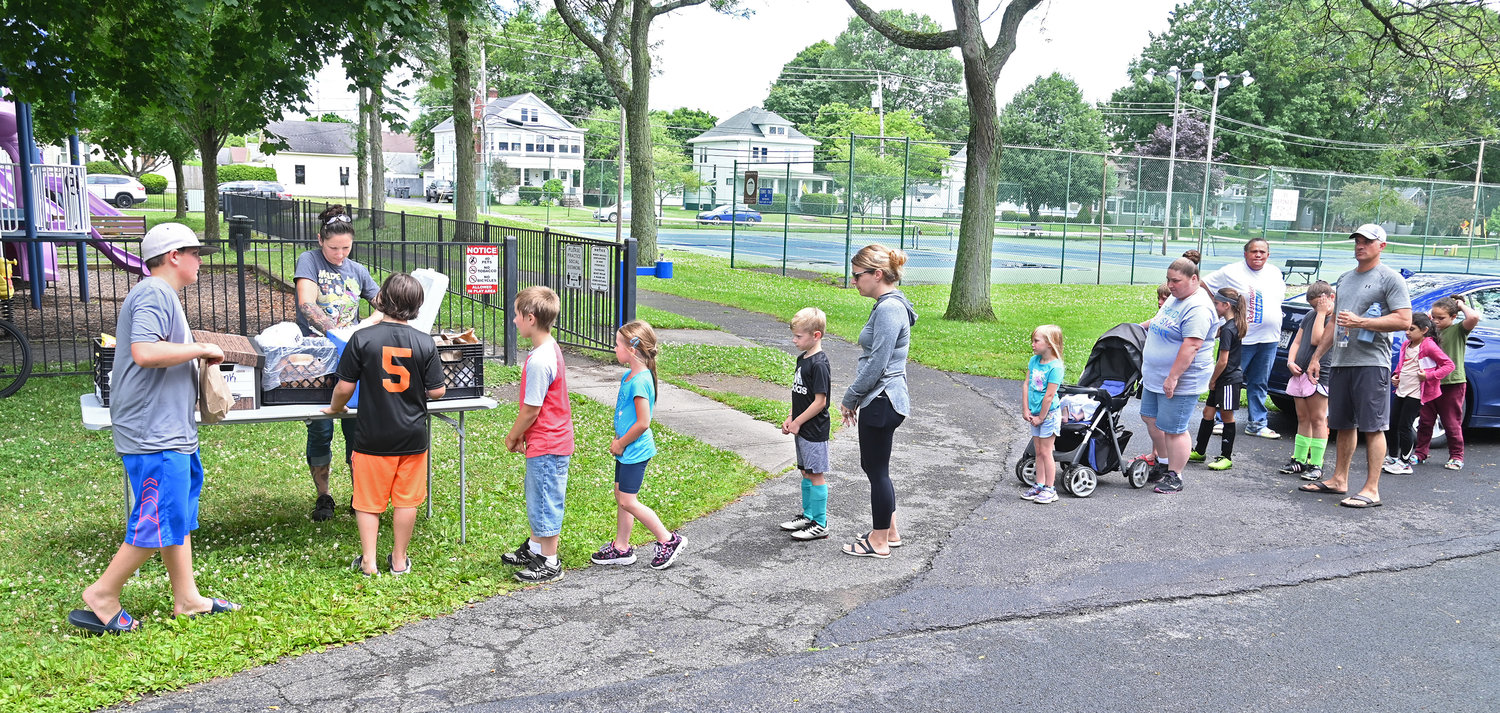 Children and parents line up for lunches at Franklyn’s Field with Rome City School District employee Hillary Young serving up turkey sub sandwiches, fruit cups, potato chips, milk and juices.  Lunches are part of the federally-funded 2022 Summer Food Service program.