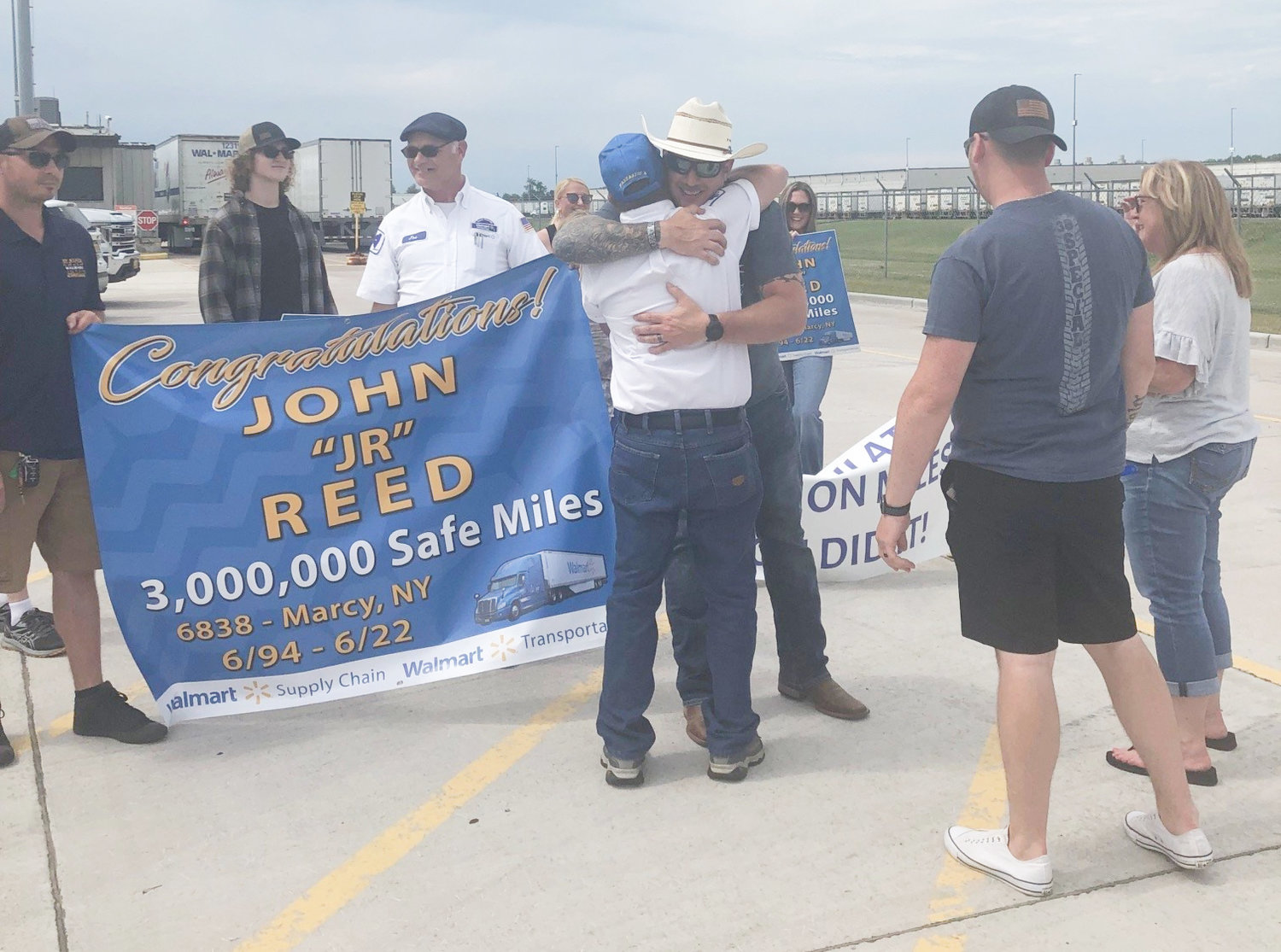 Walmart celebrated and congratulated one of its Distribution Center drivers for driving three million miles safely over the course of his 28 year career. Pictured is John Reed in white, receiving a hug from his son.