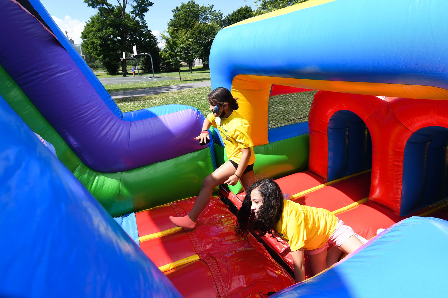 Camila Santana and Michaela Harrington run through an inflatable obstacle course during the Boilermaker Youth Olympics on Thursday at T.R. Proctor Park in Utica.