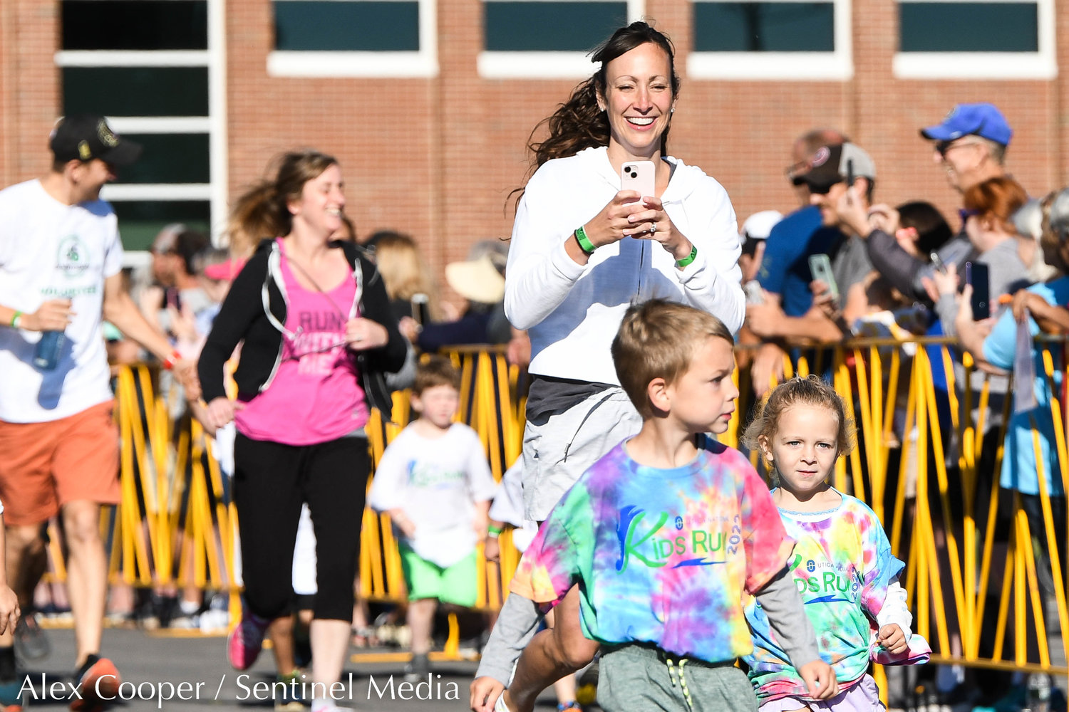 A woman records her children while participating in the Utica National Kids Run at Mohawk Valley Community College in Utica on Saturday.