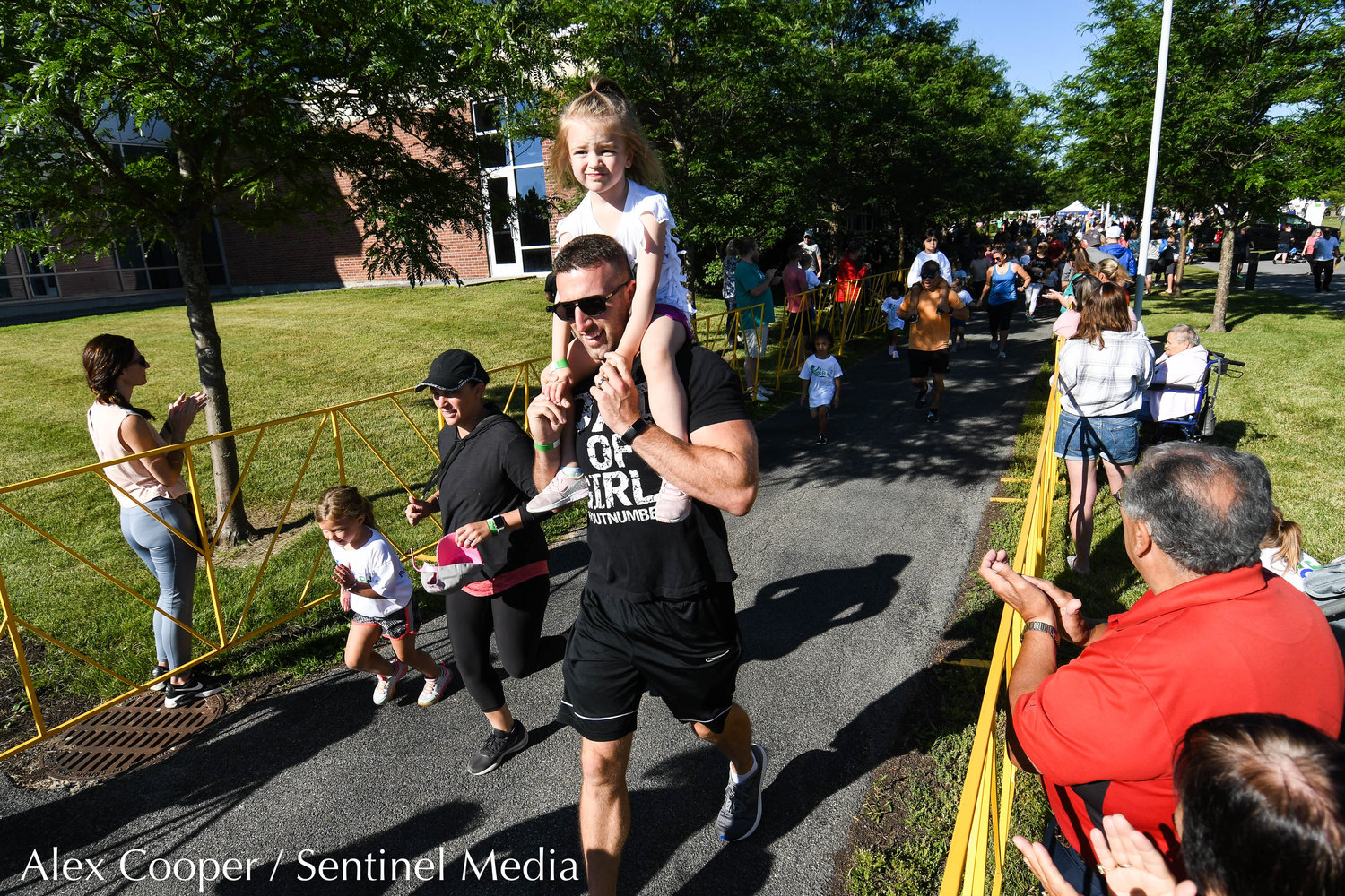A young girl catches a ride on her dad's shoulders during the Utica National Kids Run at Mohawk Valley Community College in Utica on Saturday.