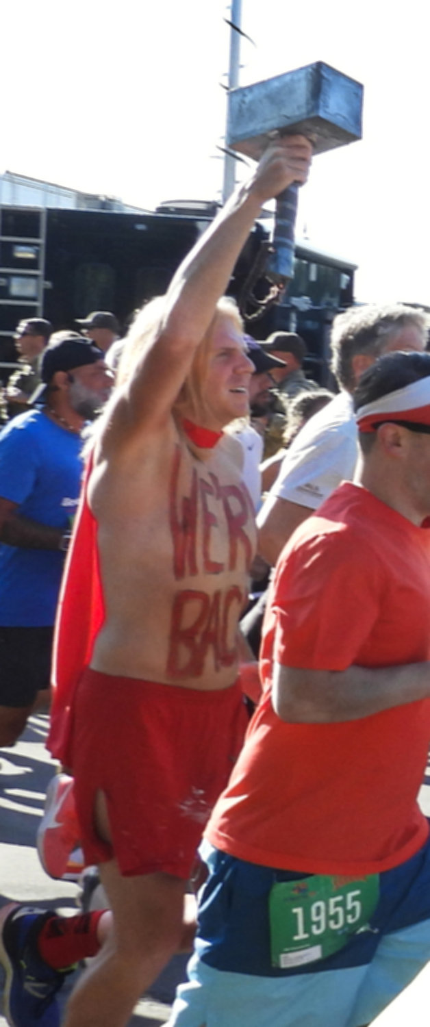A runner carrying Thor's hammer with the words "We're Back" painted on his chest runs in the 45th Boilermaker Road Race on Sunday, July 10 in Utica.
