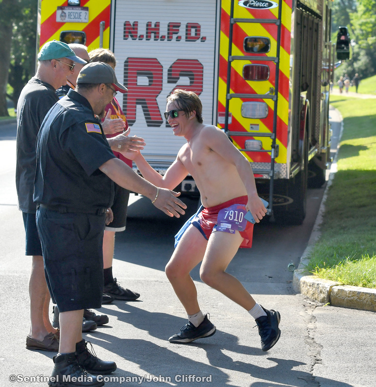 15k runner Daniel Monahan of New Hartford, NY, celebrates with New Hartford firemen after  coming down Master Garden Road on to  Memorial Parkway during the 45th Boilermaker Road Race.