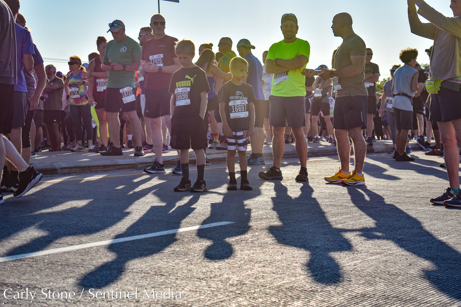 Pictured from left to right, young racers Daniel and Ellis Dziuban cast an impactful shadow next to Billy Gibson and Jeremy Dziuban as they wait to participate in the 2022 Boilermaker 5K.