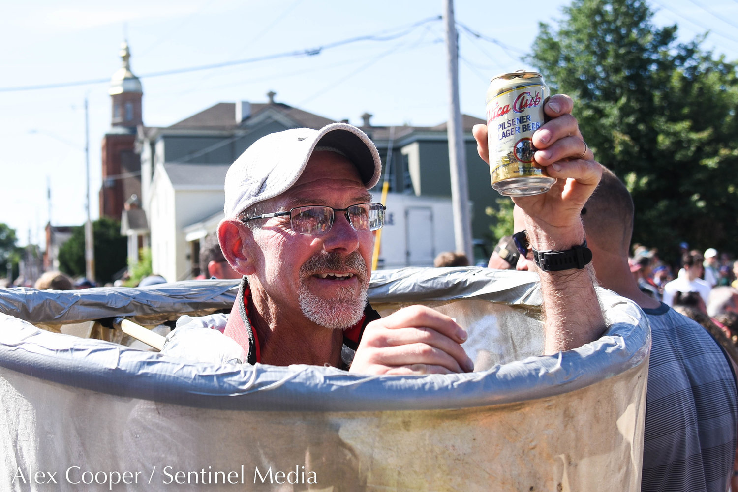 A man celebrates at the Saranac Post Race Party by drinking a Utica Club.
