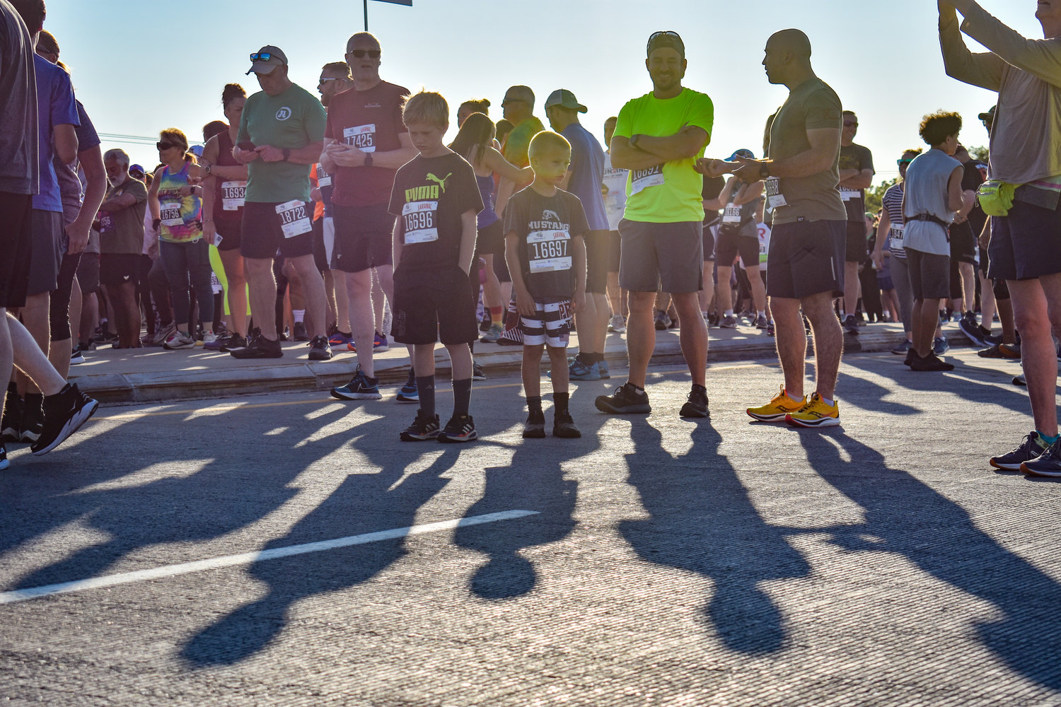 From left, young racers Daniel and Ellis Dziuban cast an impactful shadow next to Billy Gibson and Jeremy Dziuban as they wait to participate in the 2022 Boilermaker 5K.