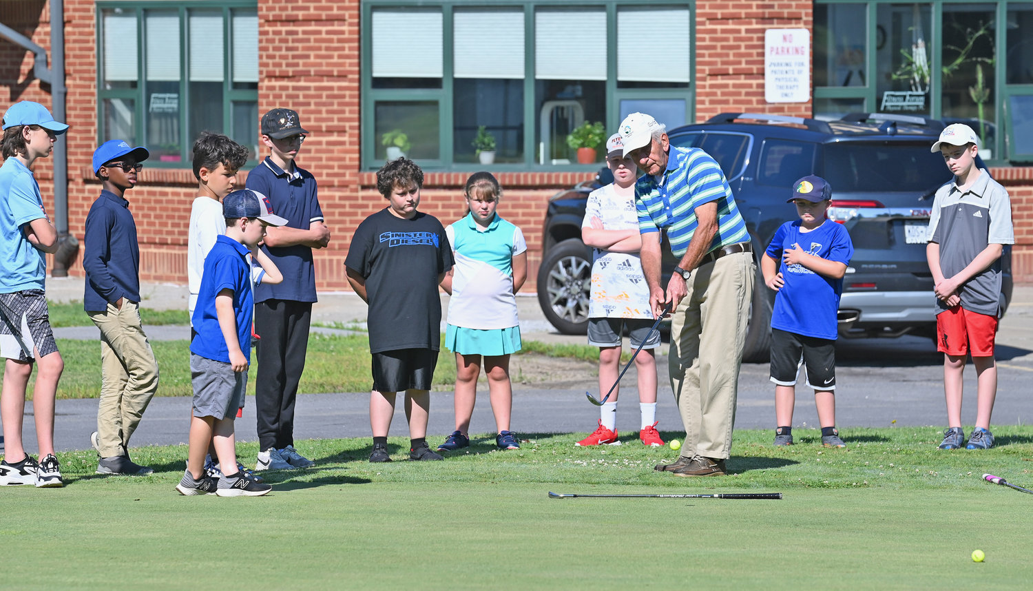 HOW TO CHIP — Golf instructor Paul Panek teaches a group of children how to chip during their second lesson on the Mohawk Glen practice green Wednesday. This is Panek’s 24th year of teaching the summer program.