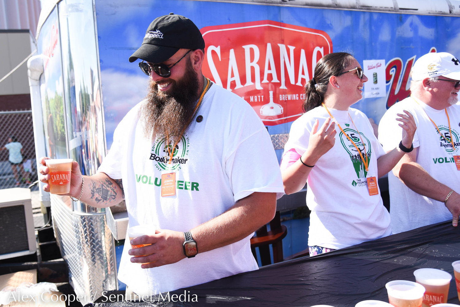 Volunteer Joseph Gonyea helps serve cold brews at the Saranac Post Race Party following the 45th Boilermaker Road Race in Utica.