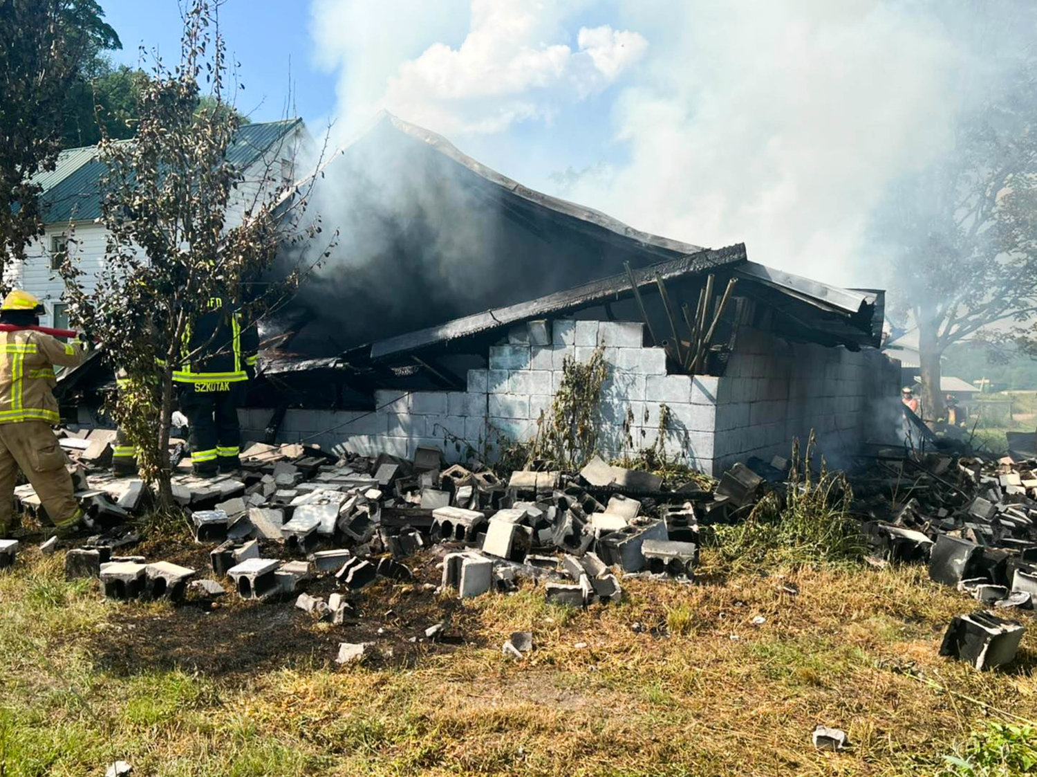 Volunteer firefighters douse what remains of a garage fire on River Road in Western Saturday afternoon. Fire officials said no one was injured and the cause remains under investigation.