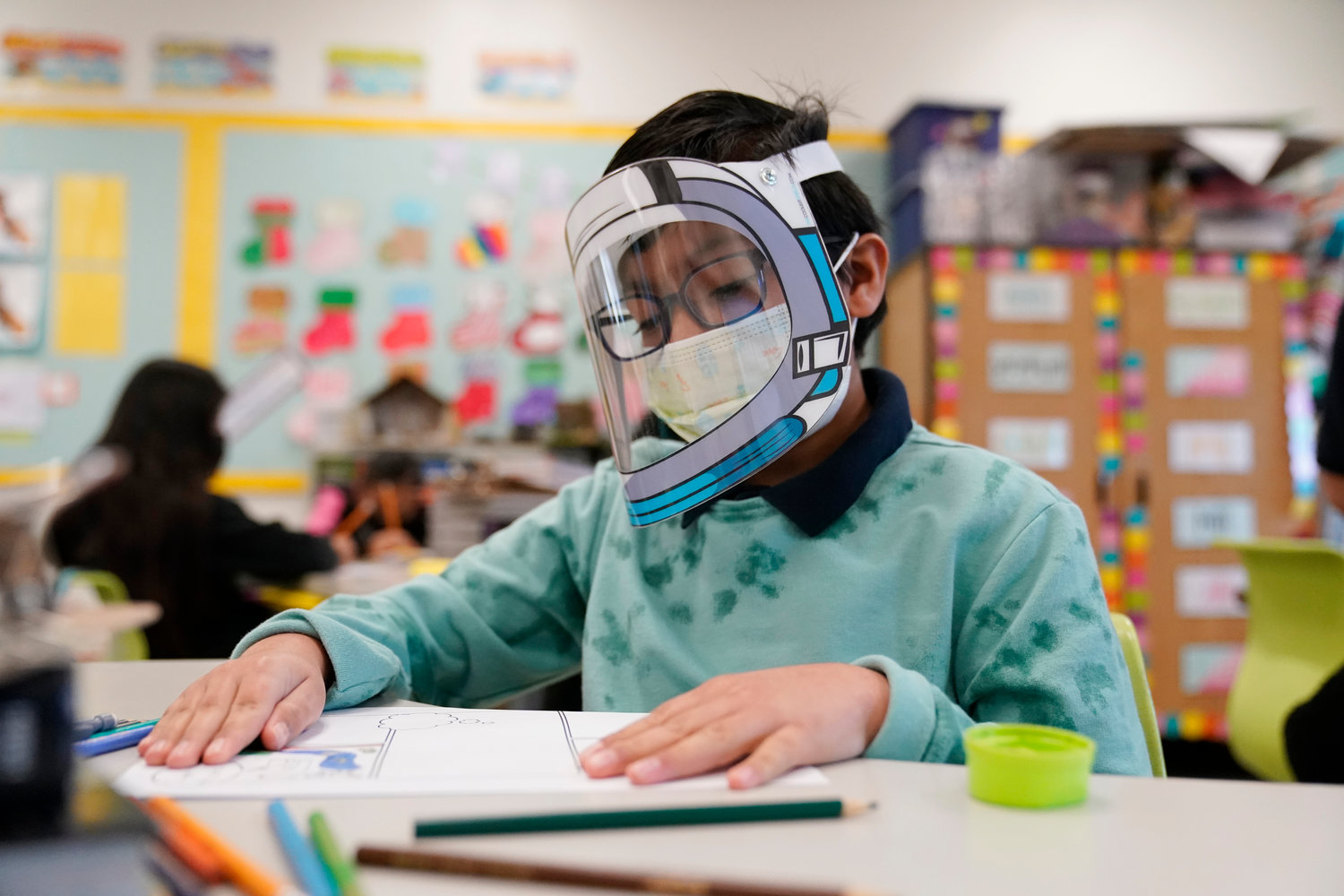 A student wears a mask and face shield in a 4th grade class amid the COVID-19 pandemic at Washington Elementary School on Jan. 12, 2022, in Lynwood, Calif. As a new school year approaches, COVID-19 infections are again on the rise, fueled by highly transmissible variants, filling families with dread. They fear the return of a pandemic scourge: outbreaks that sideline large numbers of teachers, close school buildings and force students back into remote learning.