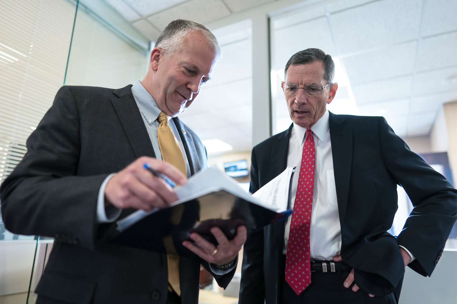 Sen. Dan Sullivan, R-Alaska, left, and Sen. John Barrasso, R-Wyo., confer just before a news conference to discuss their efforts to rescind recent Biden administration rules on the National Environmental Policy Act, at the Capitol in Washington, Tuesday, Aug. 2, 2022. (AP Photo/J. Scott Applewhite)