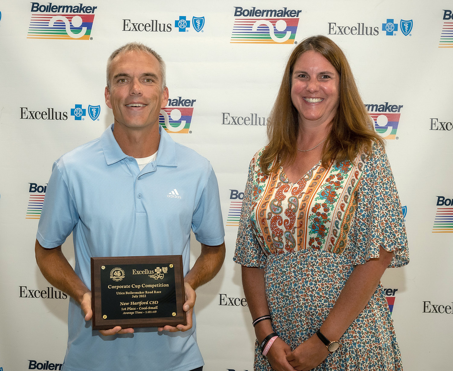 New Hartford Central School District team captain Michael Brych, left, accepts the award for the fastest co-ed small team category in the 2022 Boilermaker Road Race Corporate Cup. At right is Shayna Keller, community investments and partnerships manager, Utica region for Excellus BlueCross BlueShield, which sponsored the competition.