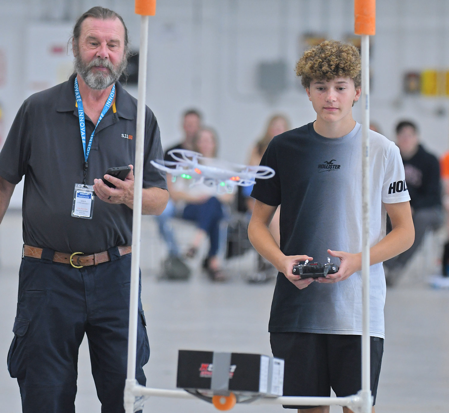 THROUGH THE POSTS — Rome Free Academy sophomore Joey Fiorini navigates his drone to one of the obstacles as drone camp instructor Bill Judycki keeps the time during the Directorate STEM Outreach Program’s Drone Camp in the hangar at Innovare Advancement Center on Friday, Aug. 5, 2022.